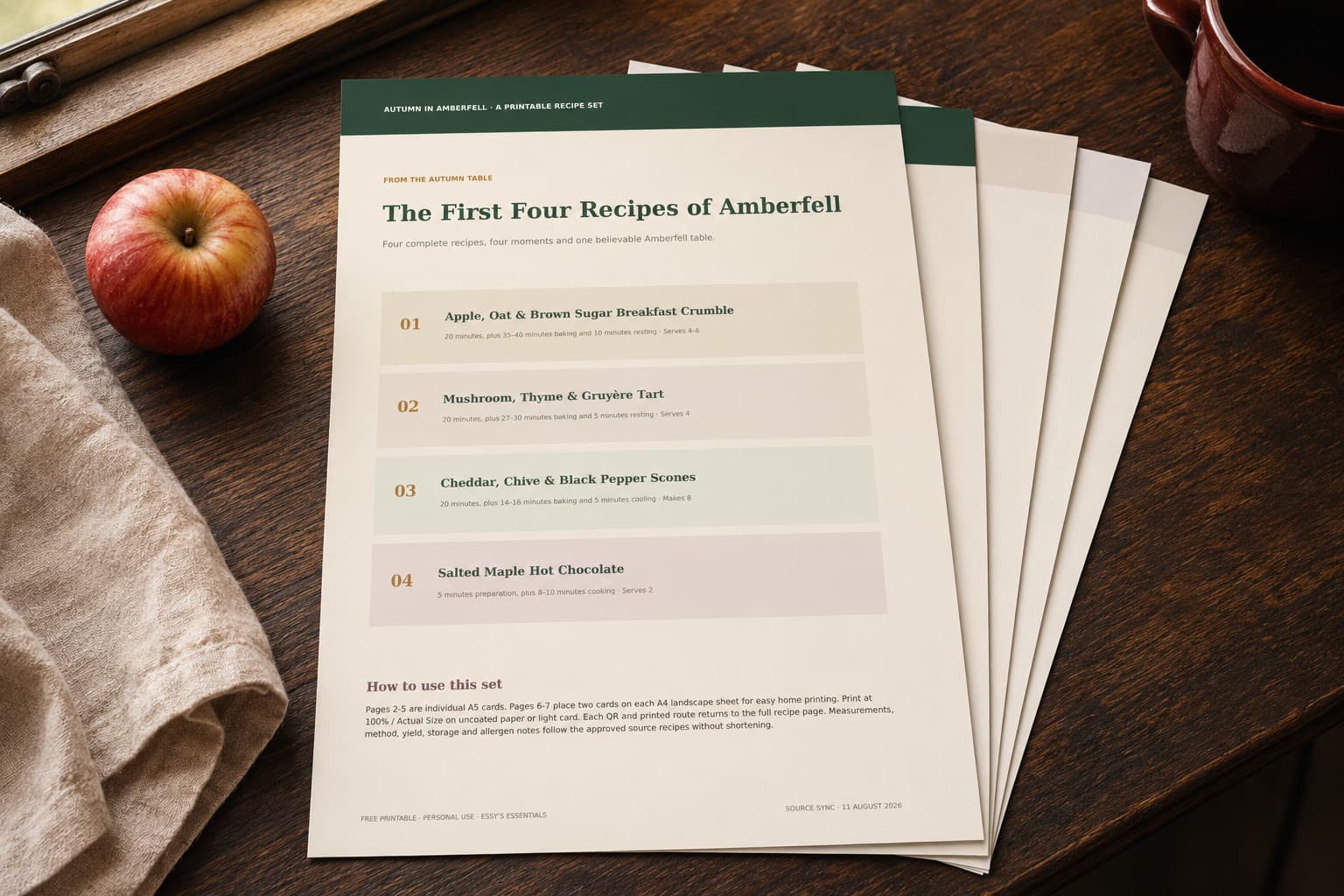 The First Four Recipes of Amberfell printable set fanned on a dark oak kitchen table.