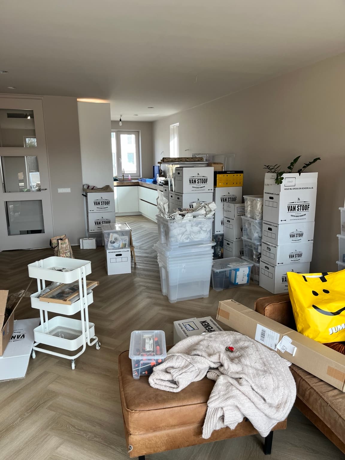 Living room and kitchen during the first weeks after moving, with boxes and temporary belongings.