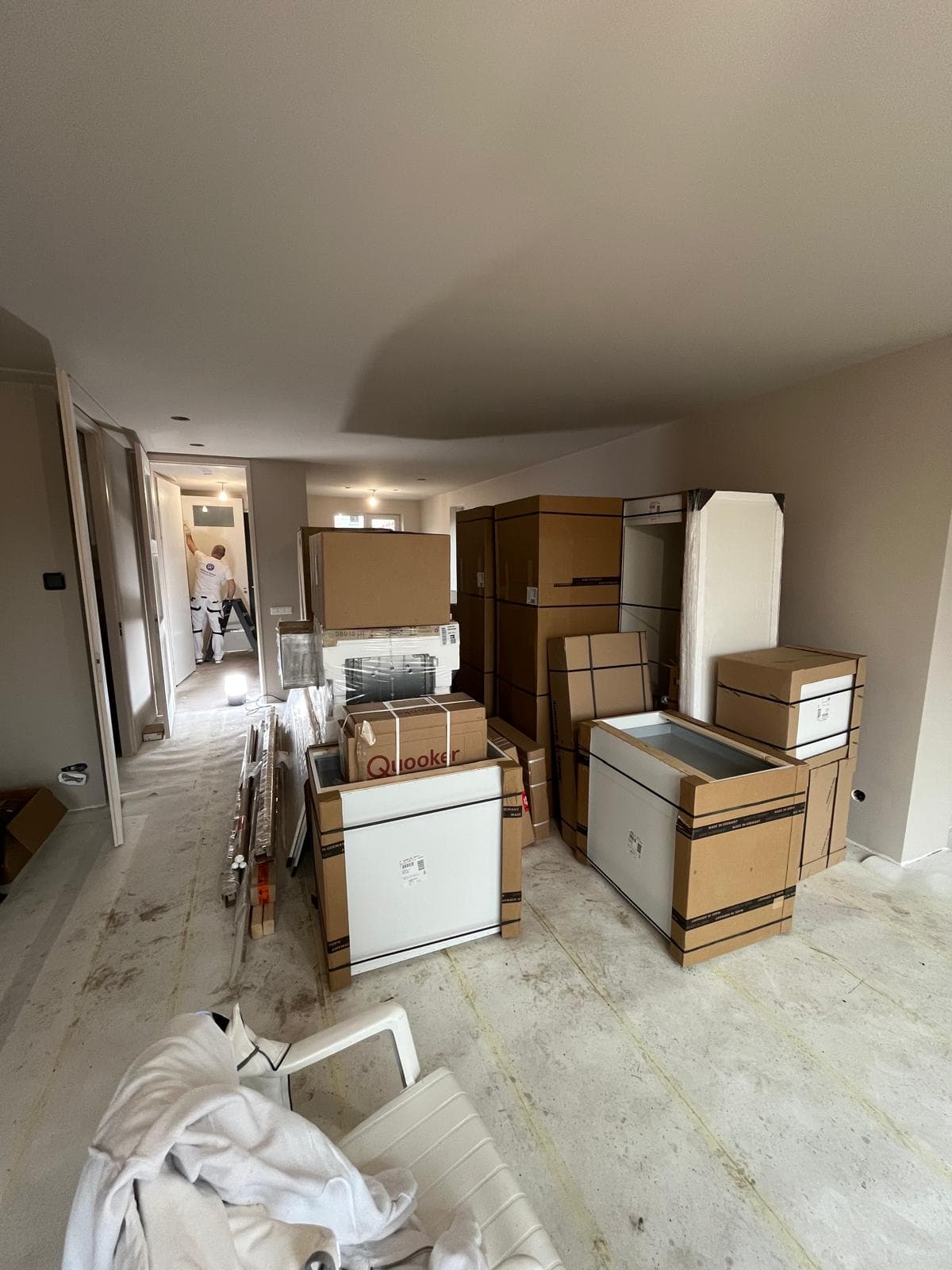 New home filled with boxed kitchen components while a painter continues working.