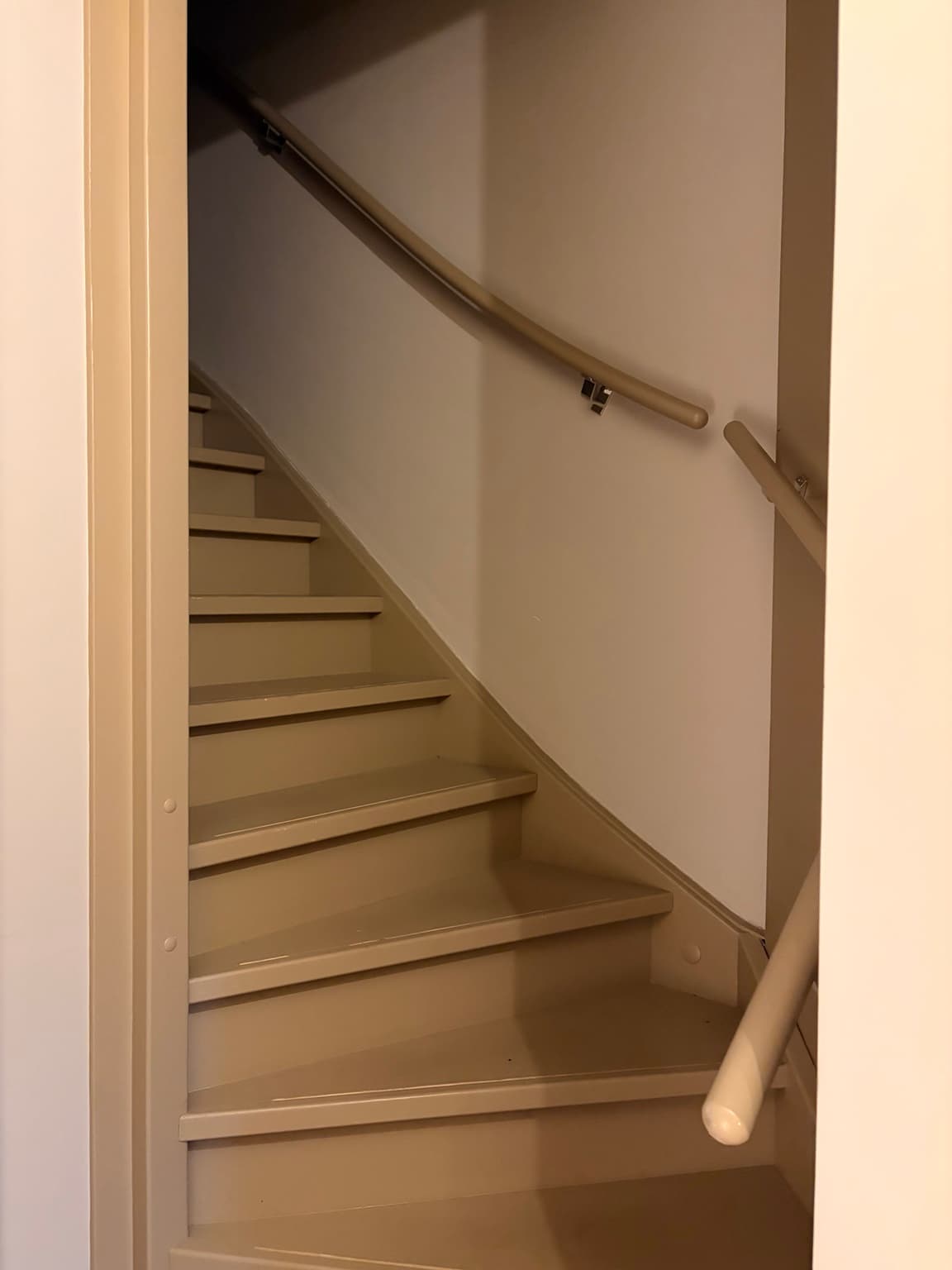 Finished staircase painted in a warm brown shade with matching handrails.