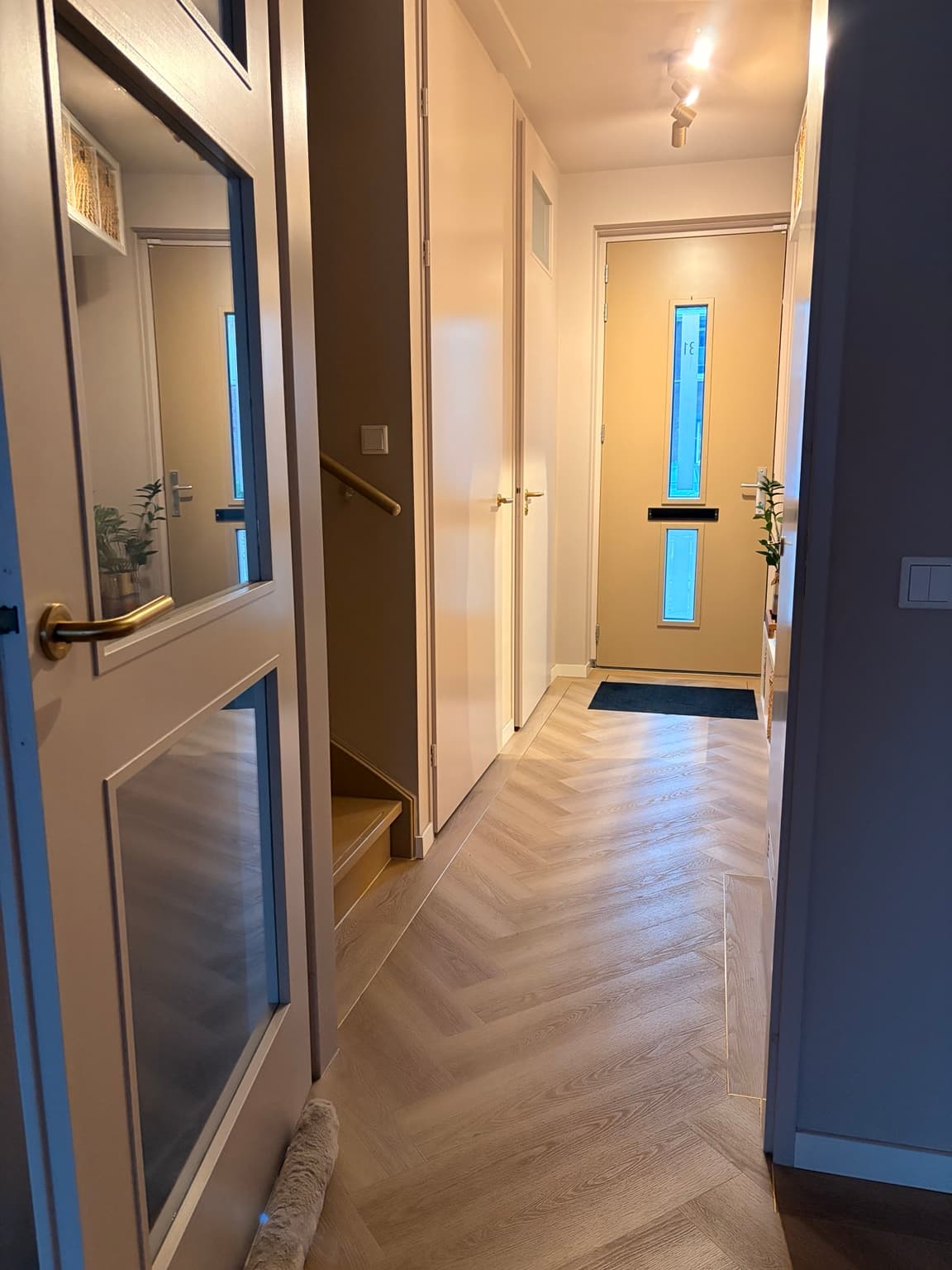 Continuous herringbone floor running through a hallway without raised thresholds.