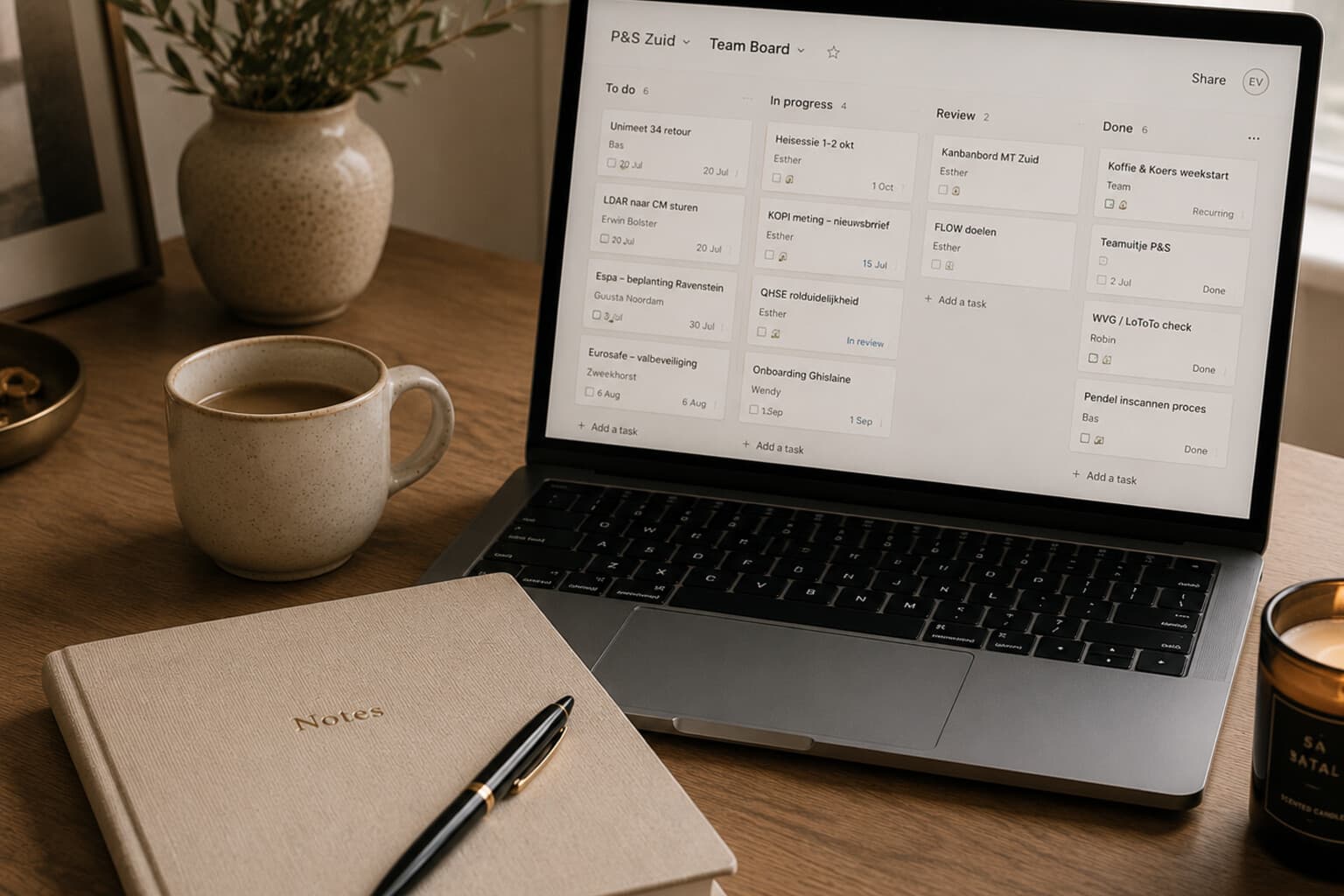 A laptop showing a simple shared task board beside a notebook on a desk.