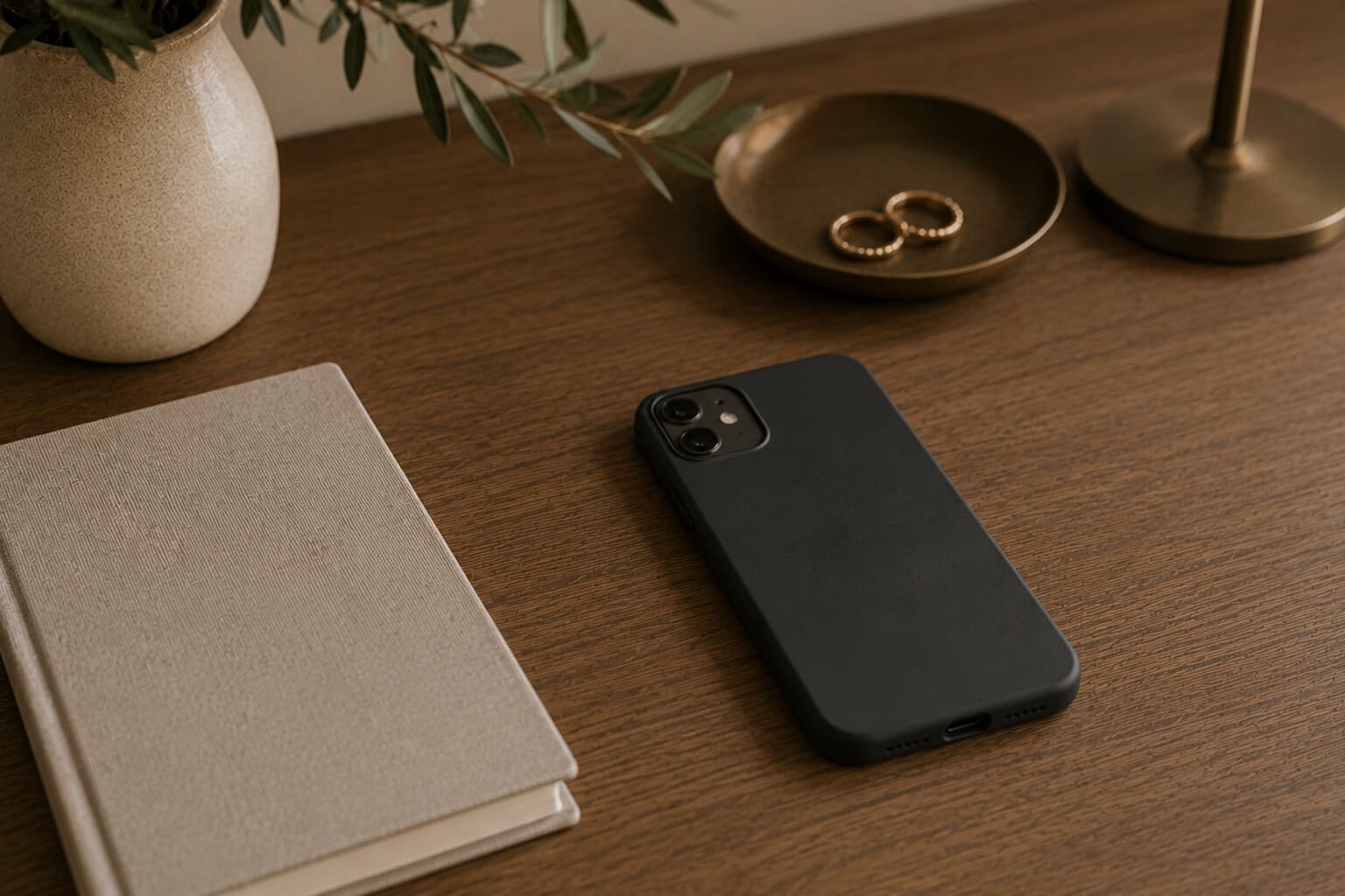 A single phone resting face-down on a quiet desk beside a closed notebook.