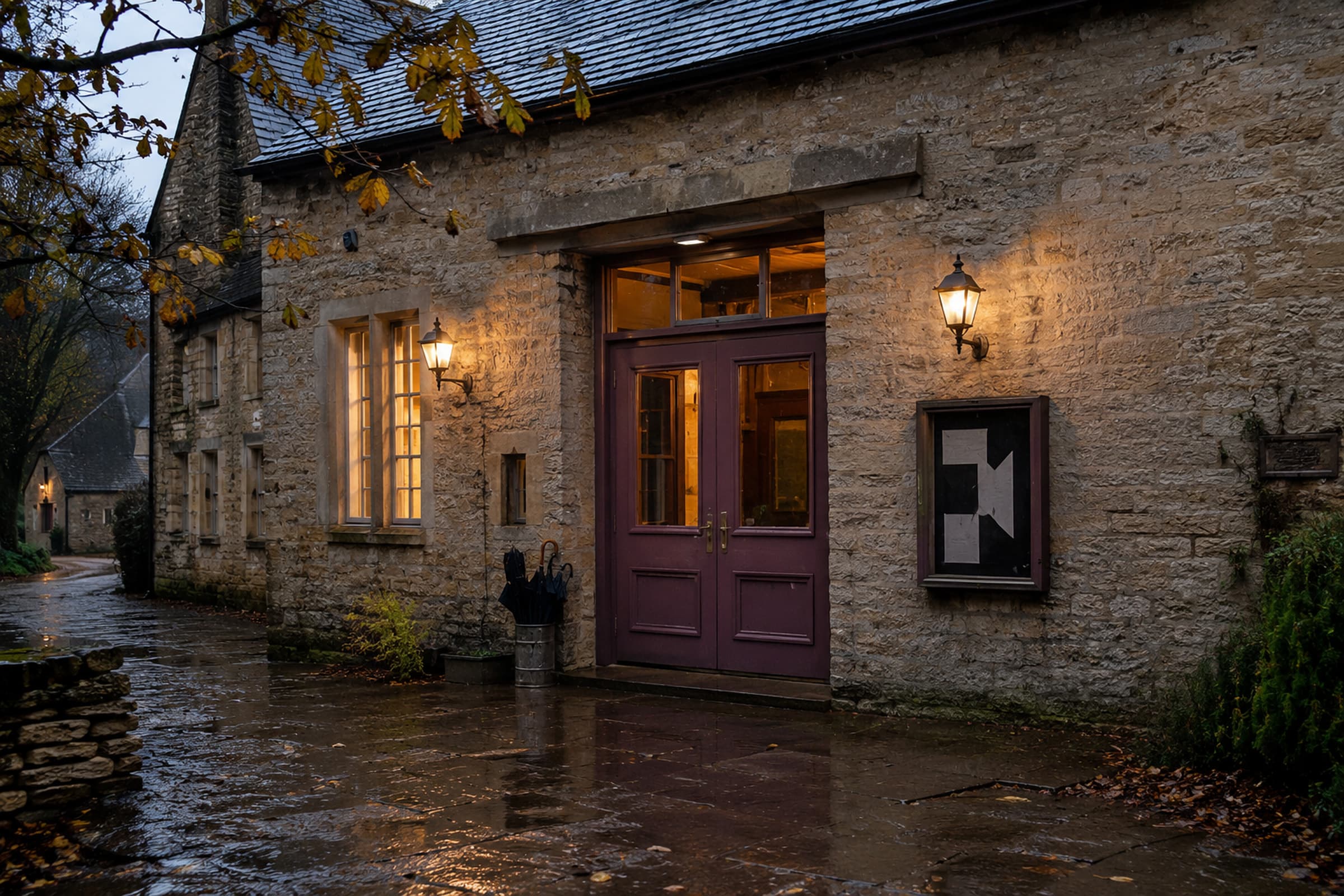 The Lantern Hall with muted plum doors, brass lamps and a warm foyer on a wet autumn evening.