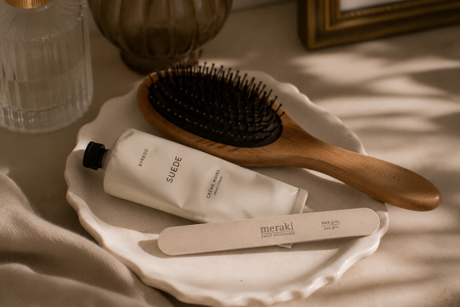 A small set of everyday grooming tools - hairbrush, hand cream and nail file - arranged neatly.