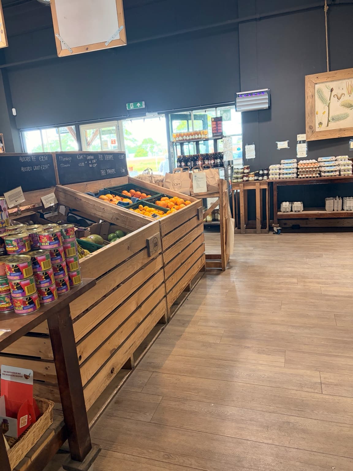Interior of a farm shop with wooden produce crates, eggs and groceries.
