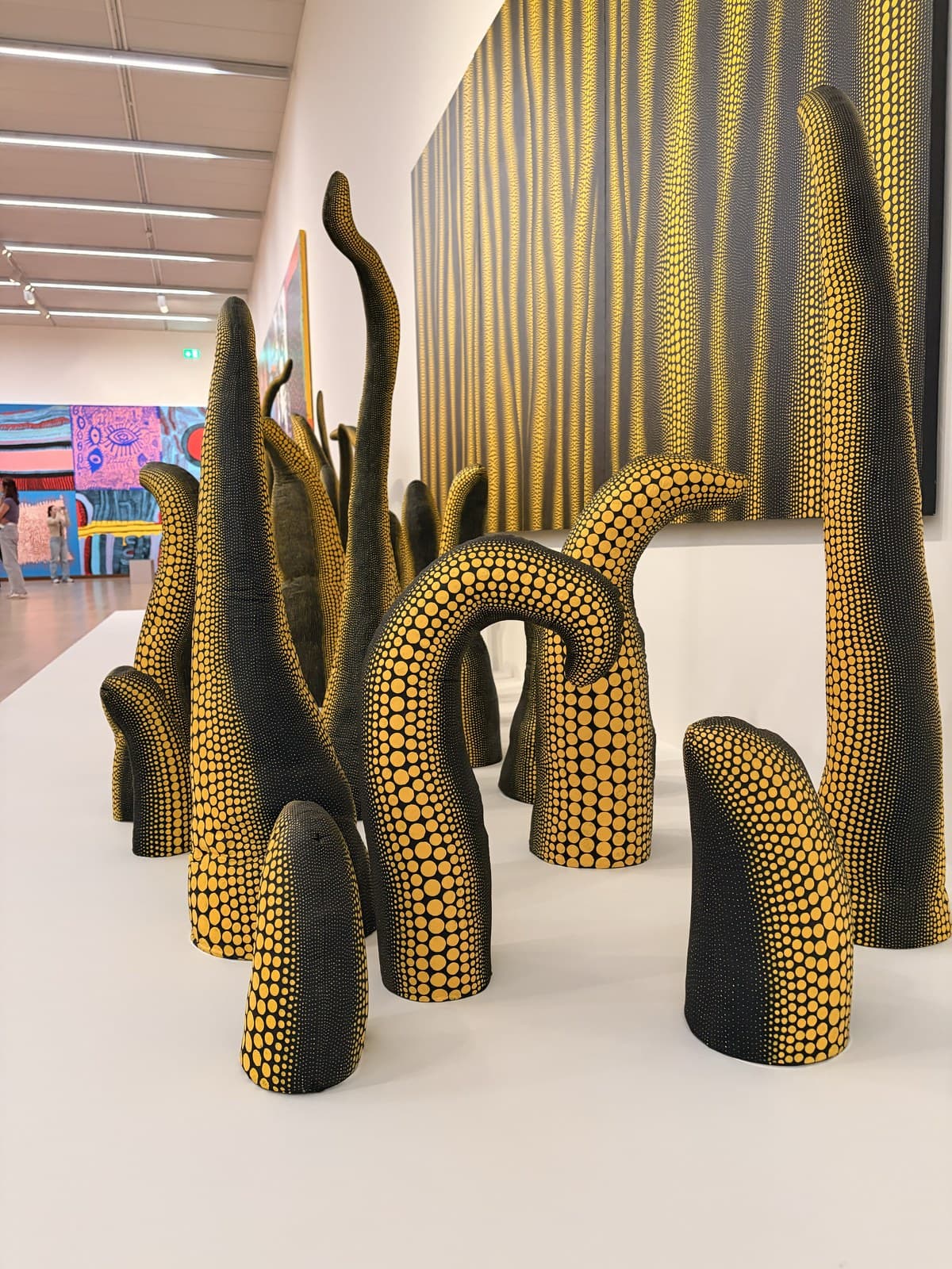 A cluster of tall black-and-yellow polka-dot tentacle sculptures rising from the gallery floor at the Yayoi Kusama exhibition, Stedelijk Museum