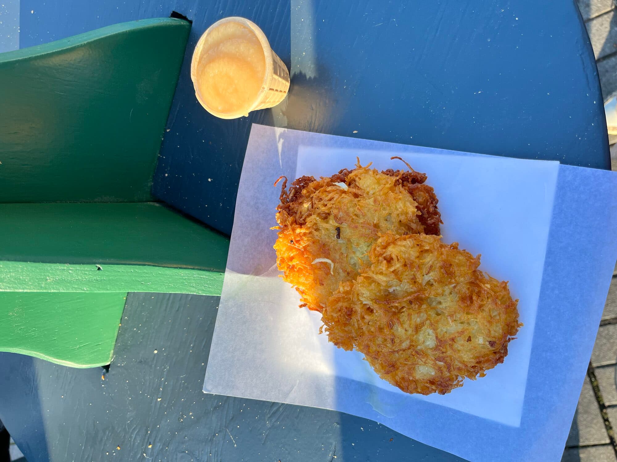 Reibekuchen potato pancakes with apple sauce on market bench seating
