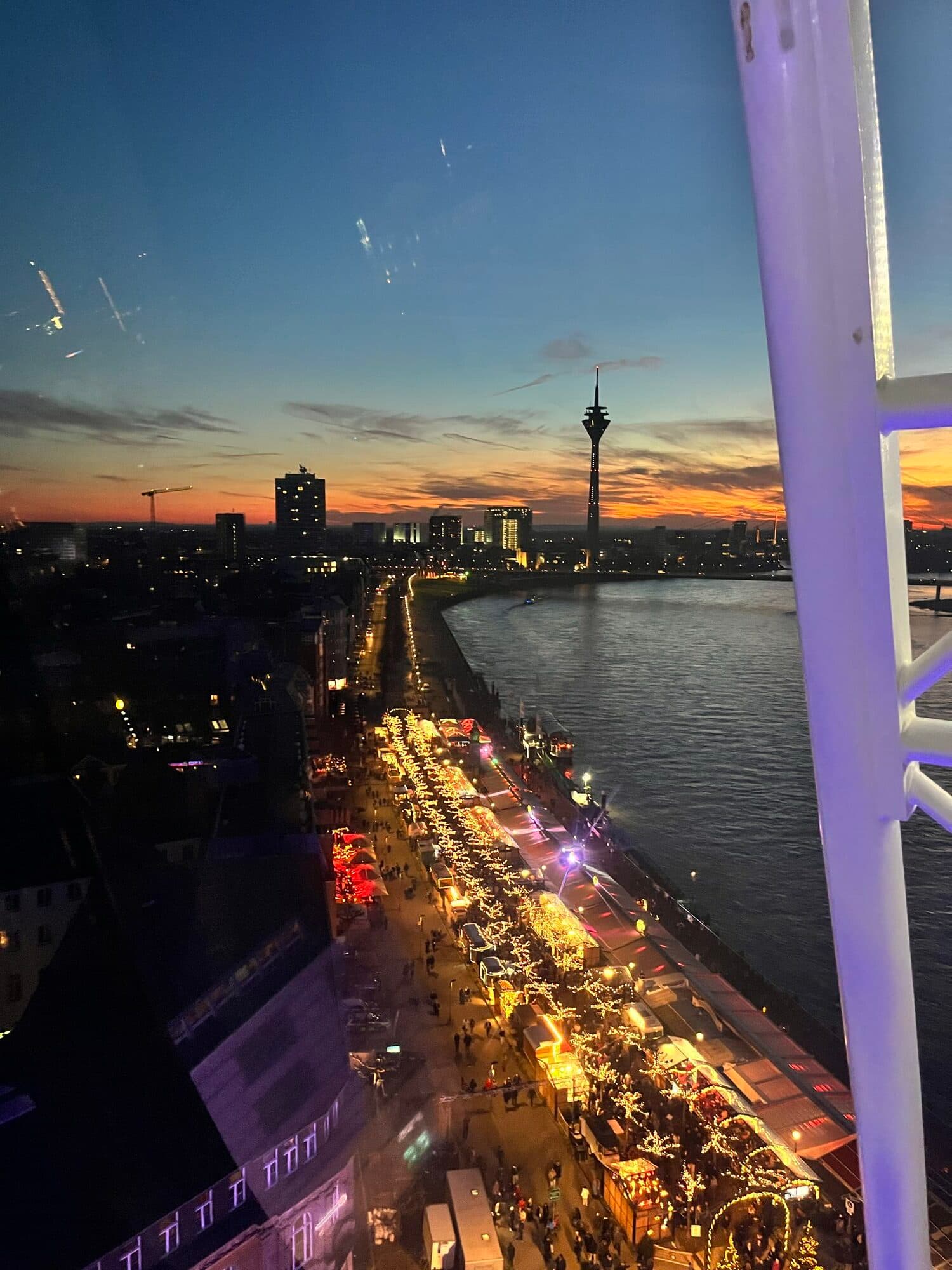 The Rhine promenade at dusk in Düsseldorf, lit up for Christmas, viewed from a ferris wheel