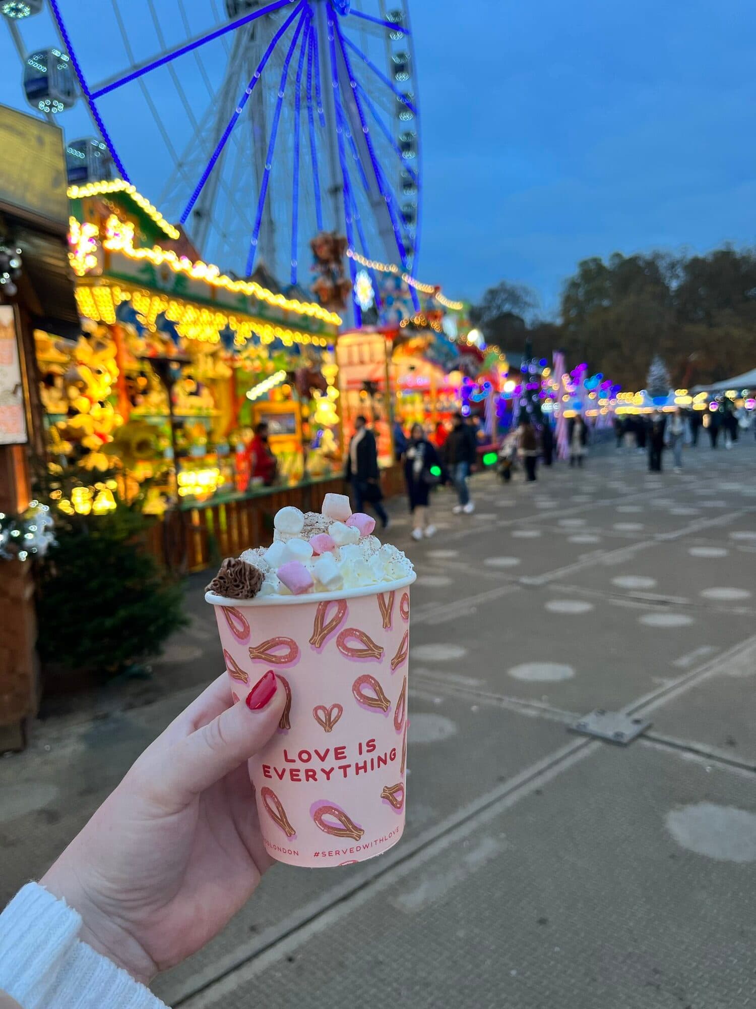 Hot chocolate at Hyde Park Winter Wonderland with the ferris wheel in the background