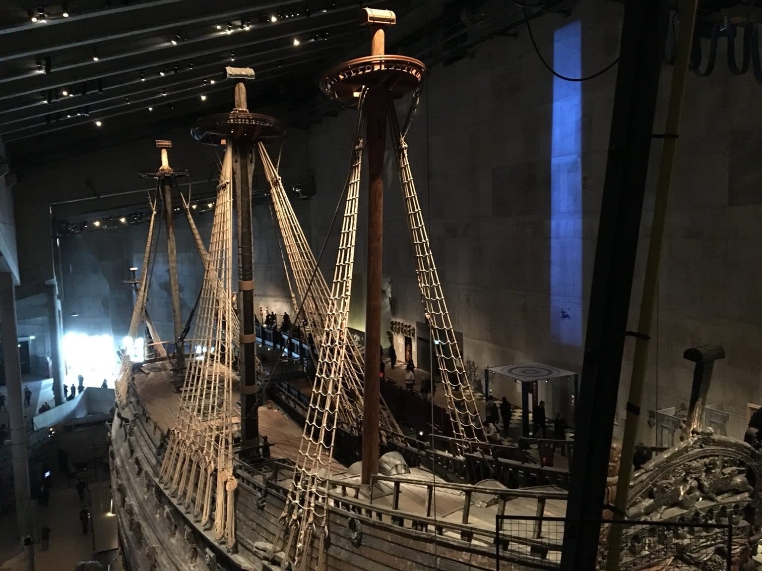 The towering masts and carved hull of the Vasa warship displayed in a dimly lit museum hall