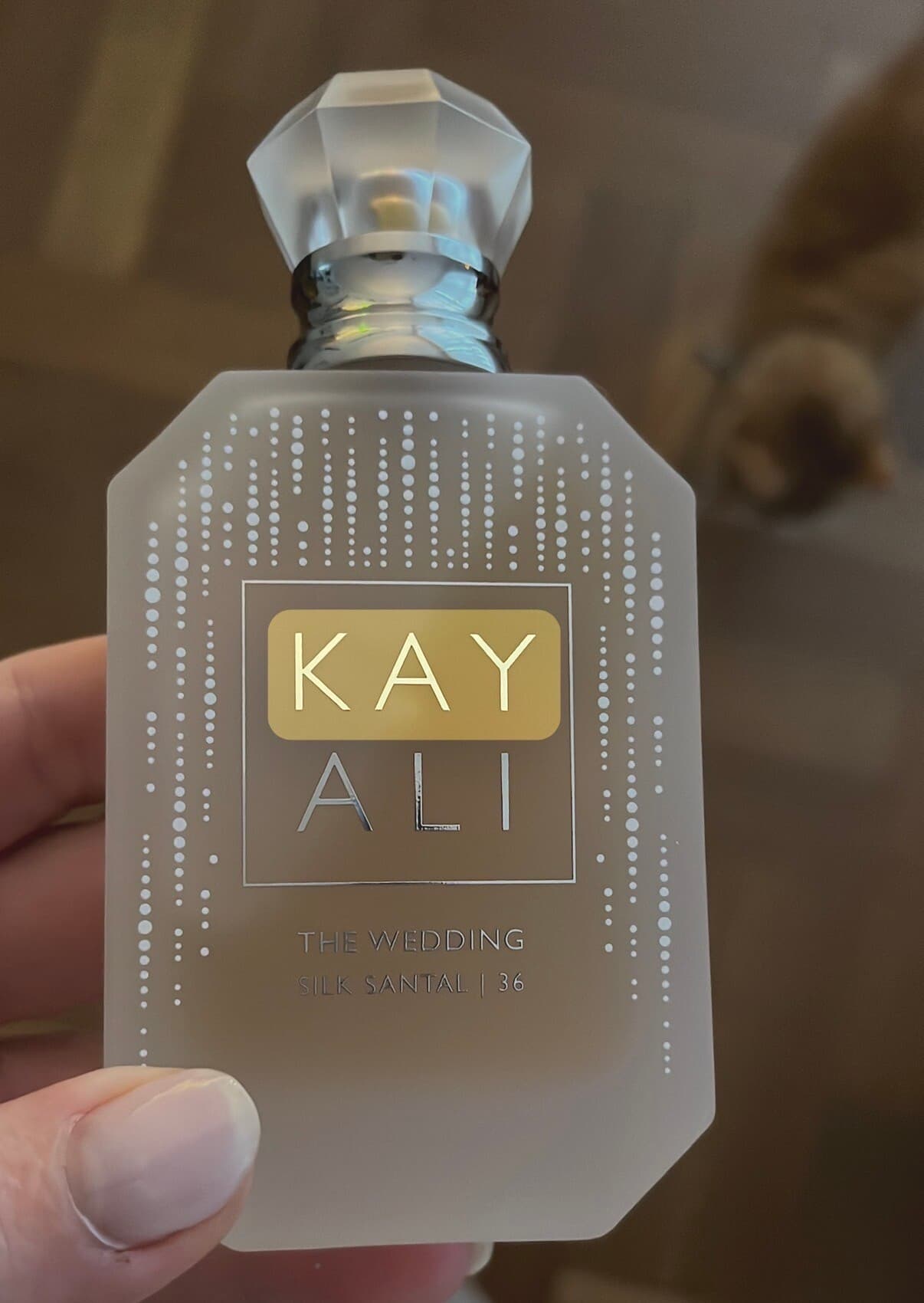 Esther holding her bottle of KAYALI The Wedding Silk Santal 36.