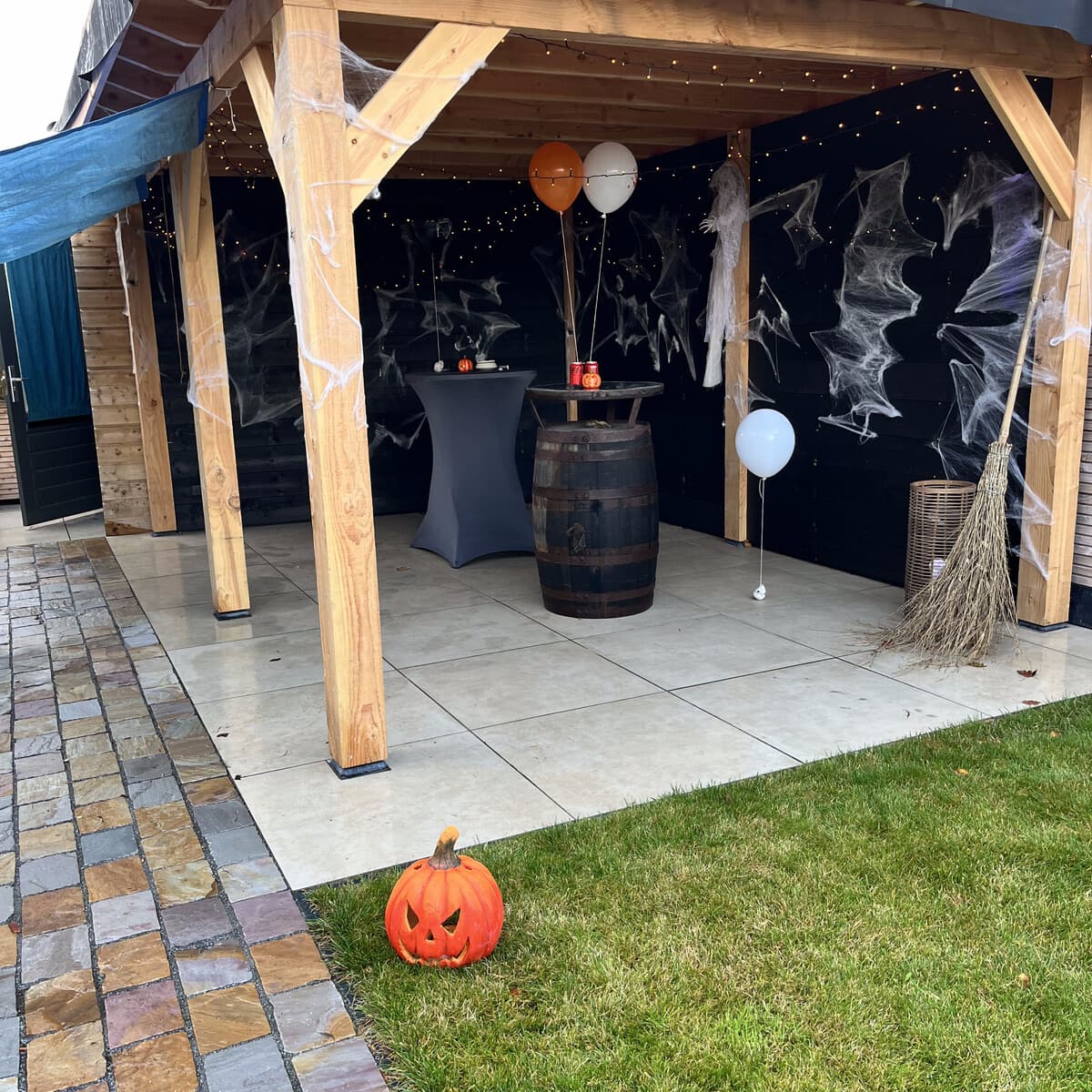 The garden pergola at Amberfell, fully dressed with cobwebs, string lights, balloons and a barrel table.