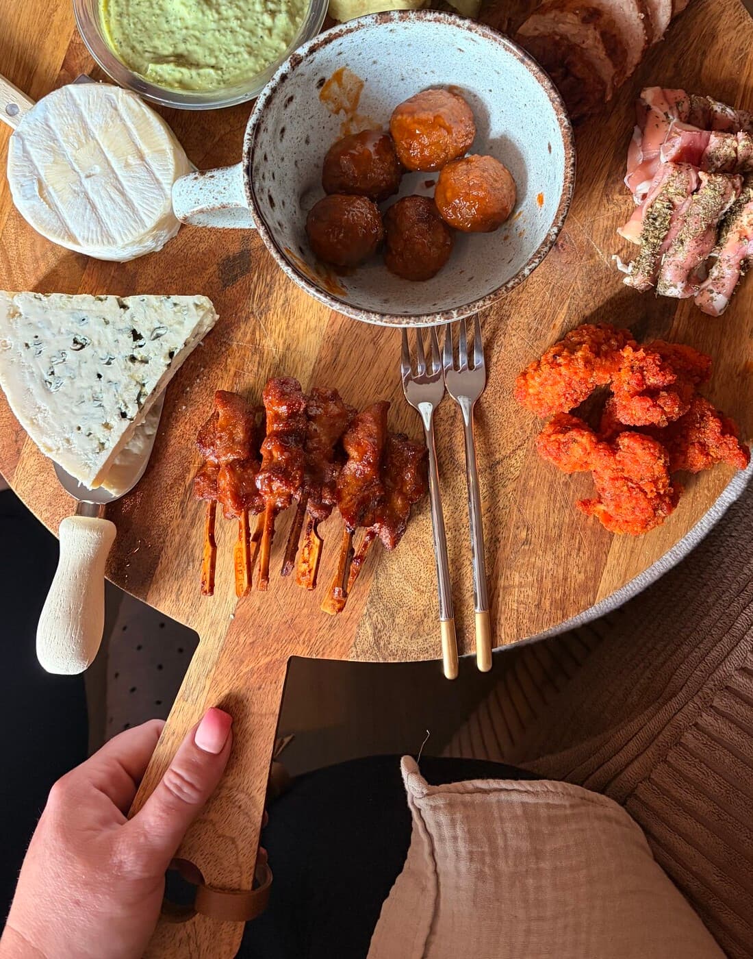 Esther holding the picky-bits board, set with cheese, meatballs and skewers, ready for guests.