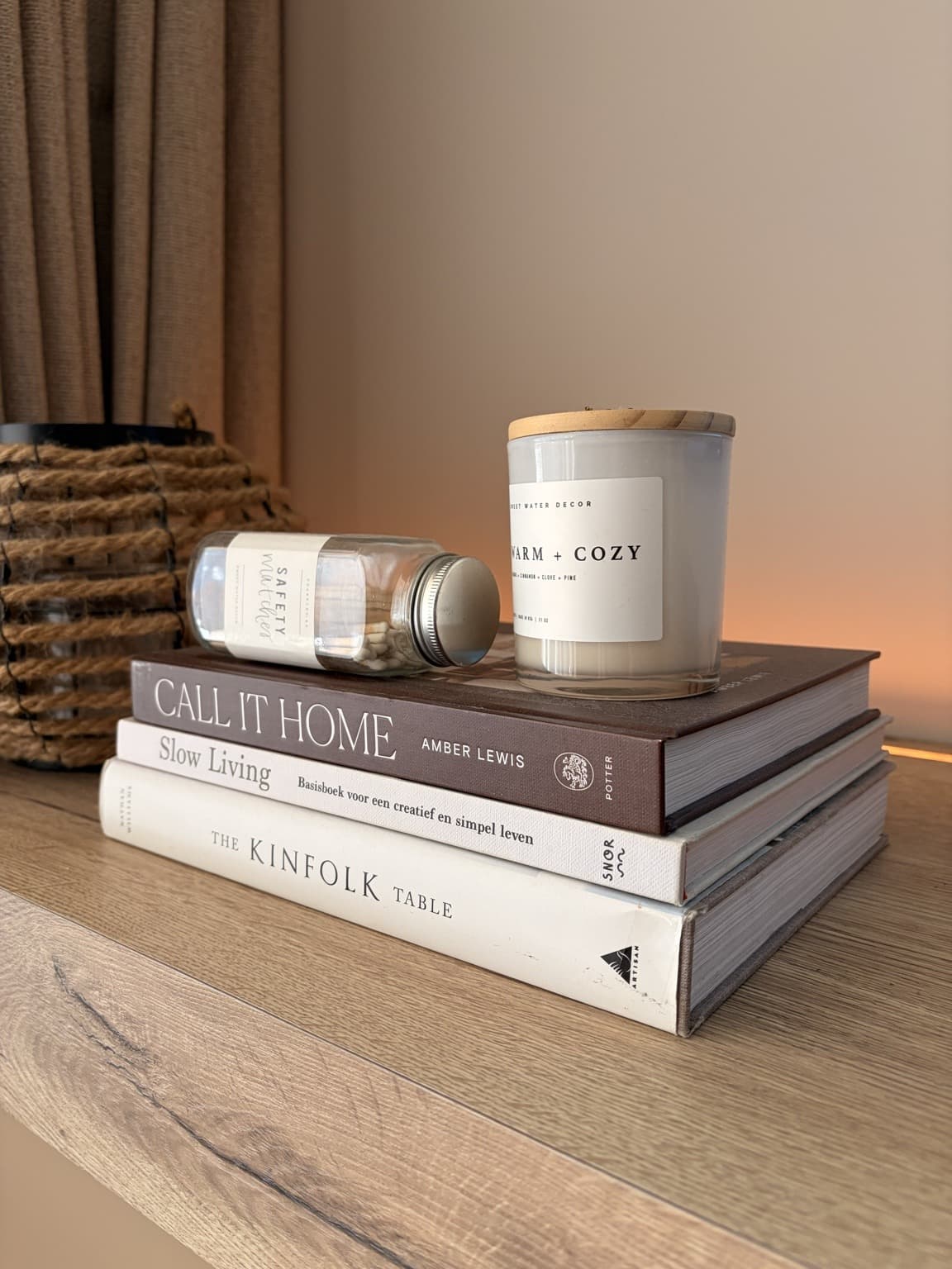 Coffee-table books stacked beneath a glass candle and a jar of long matches.