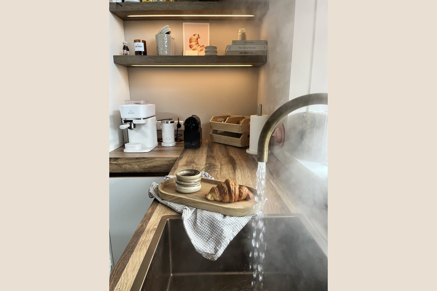 Esther's kitchen coffee corner with illuminated wooden shelves, coffee machines, books and a croissant print.