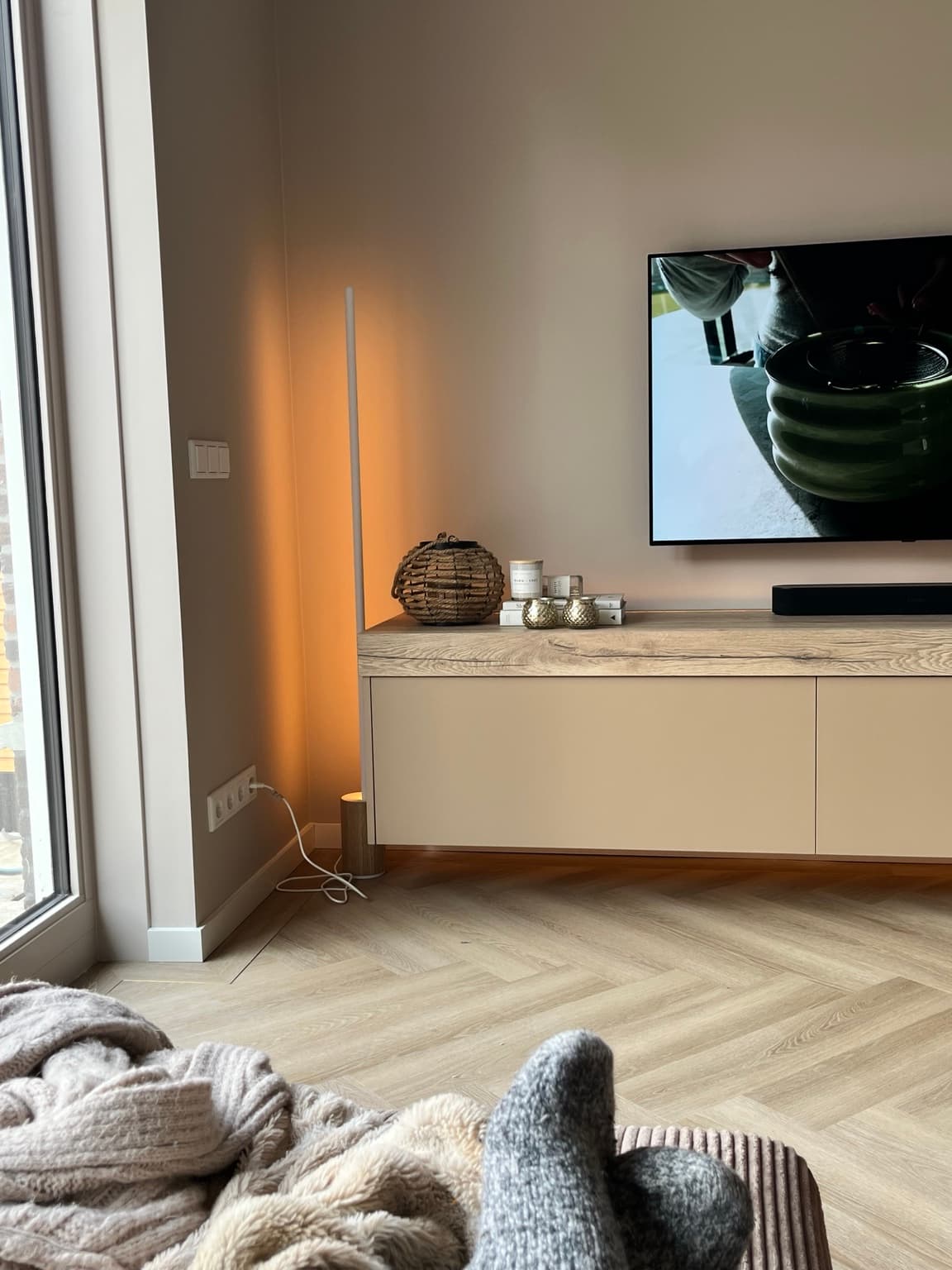 Finished living room using a slim floor lamp and warm lighting around the media wall.