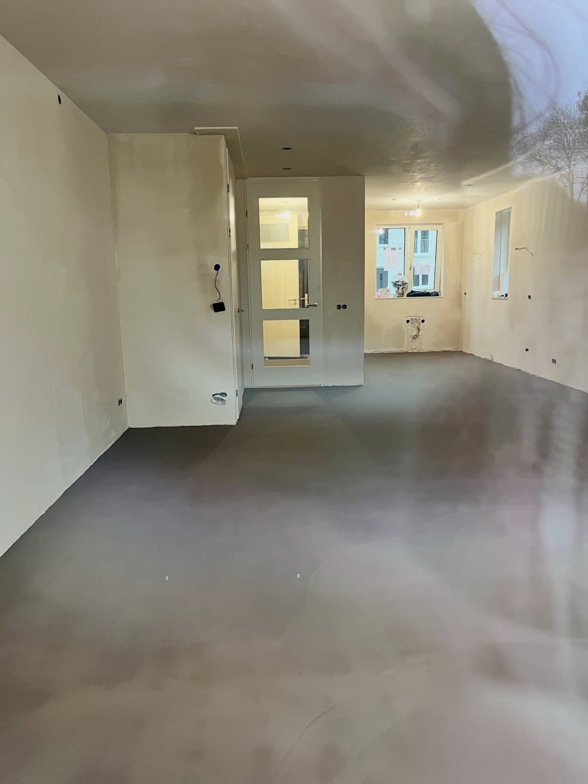 Empty new-build living space showing walls, electrical points and the future kitchen area.