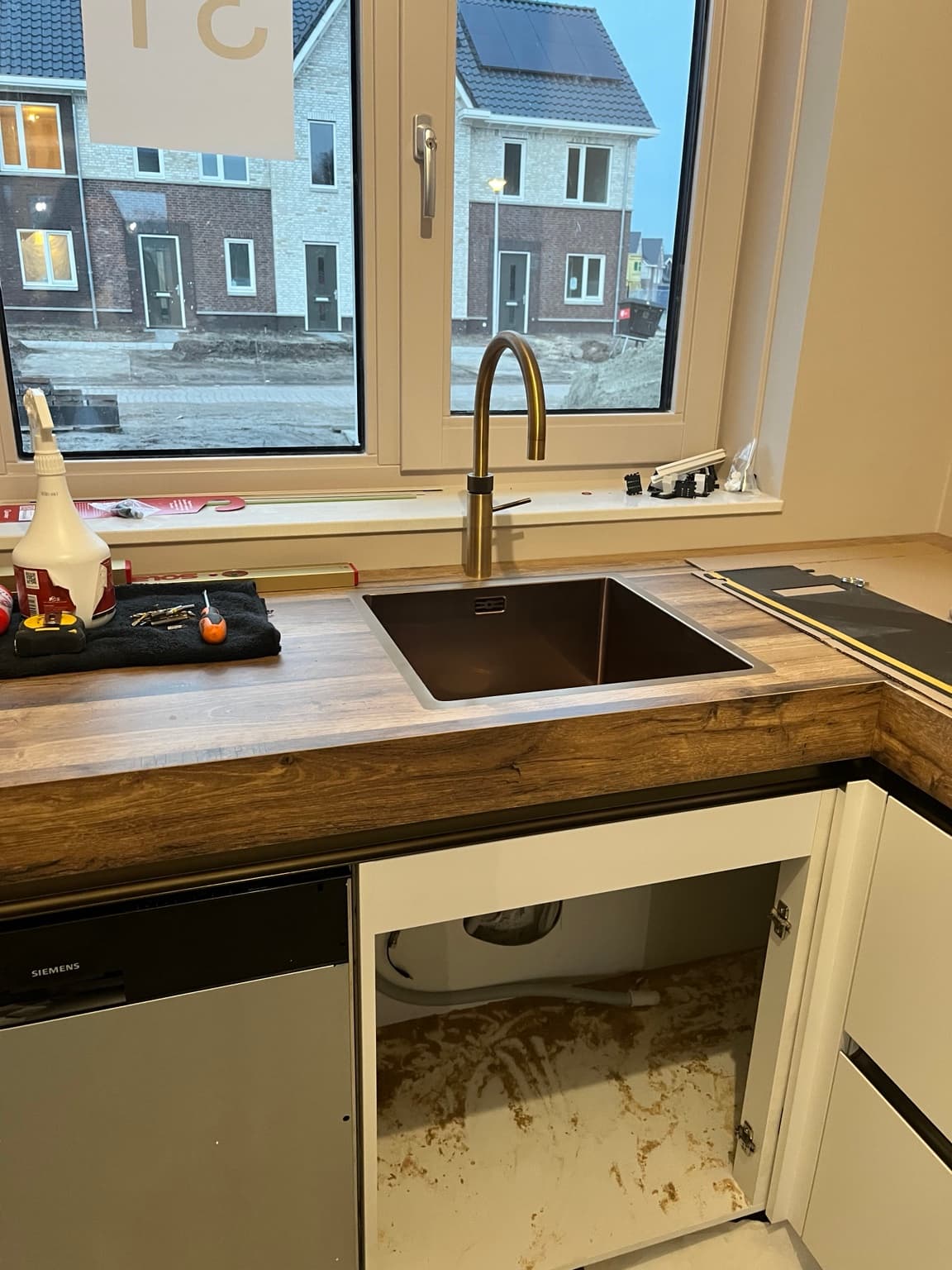 Kitchen sink and worktop during installation with unfinished appliance space below.