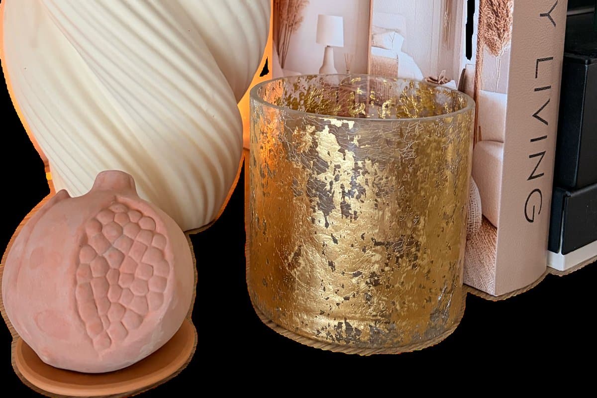 Santa Maria Novella Melograno scented terracotta pomegranate styled at home beside a vase, books and warm candlelight.