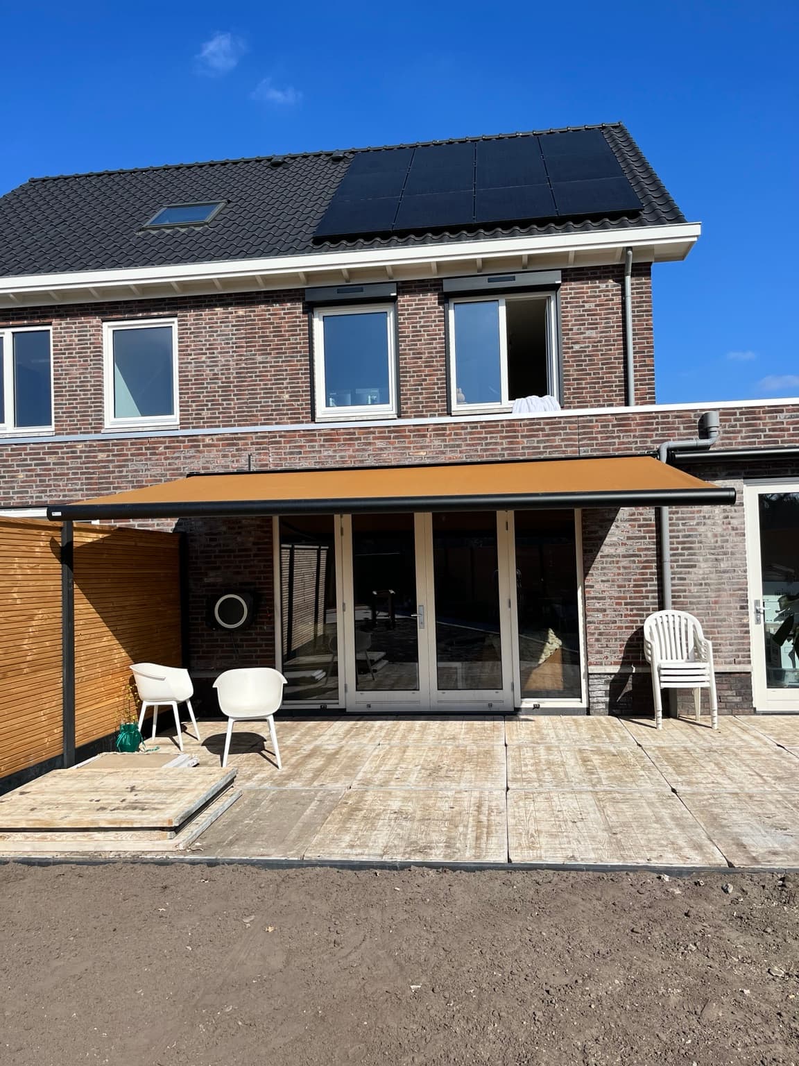 Rear of a new-build home with an extended awning above the terrace and unfinished garden.