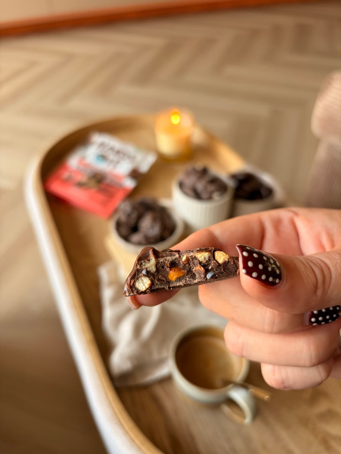 A close-up of a broken piece of Veggilaine’s Rocky Road Bites, held in hand, showing pecans, pretzel and honeycomb pieces inside the chocolate.