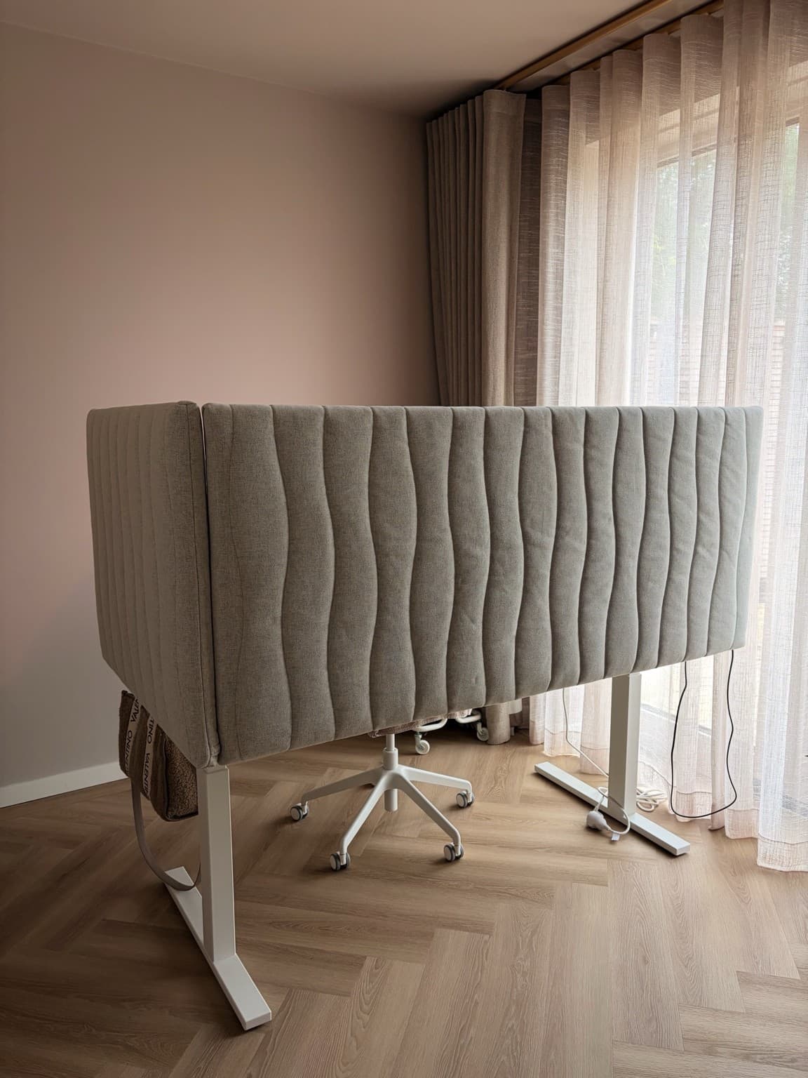 Esther’s home workspace behind a pale upholstered screen beside the living room curtains.