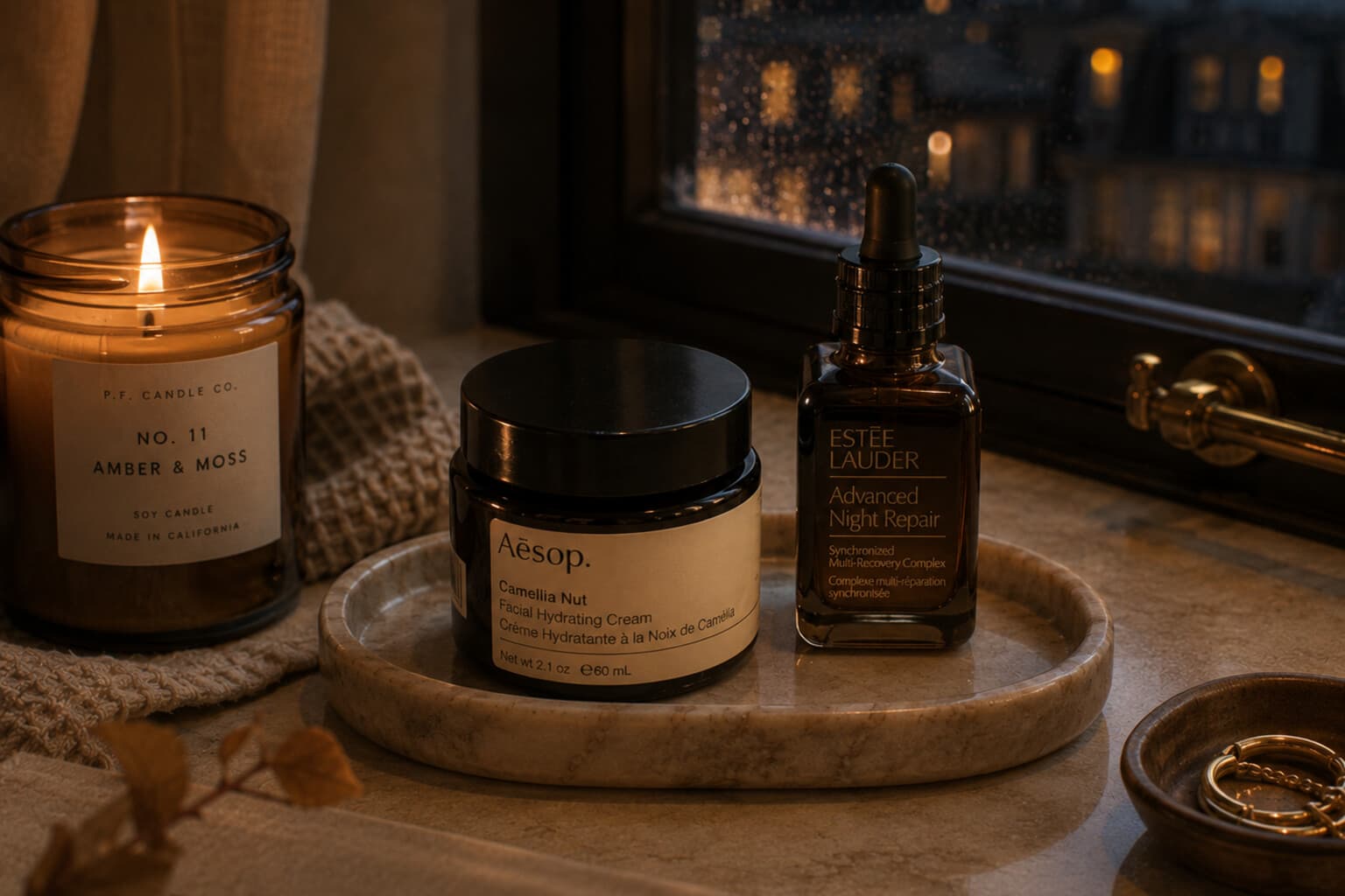 A richer evening moisturiser and facial oil beside a lit candle on a cool autumn evening.