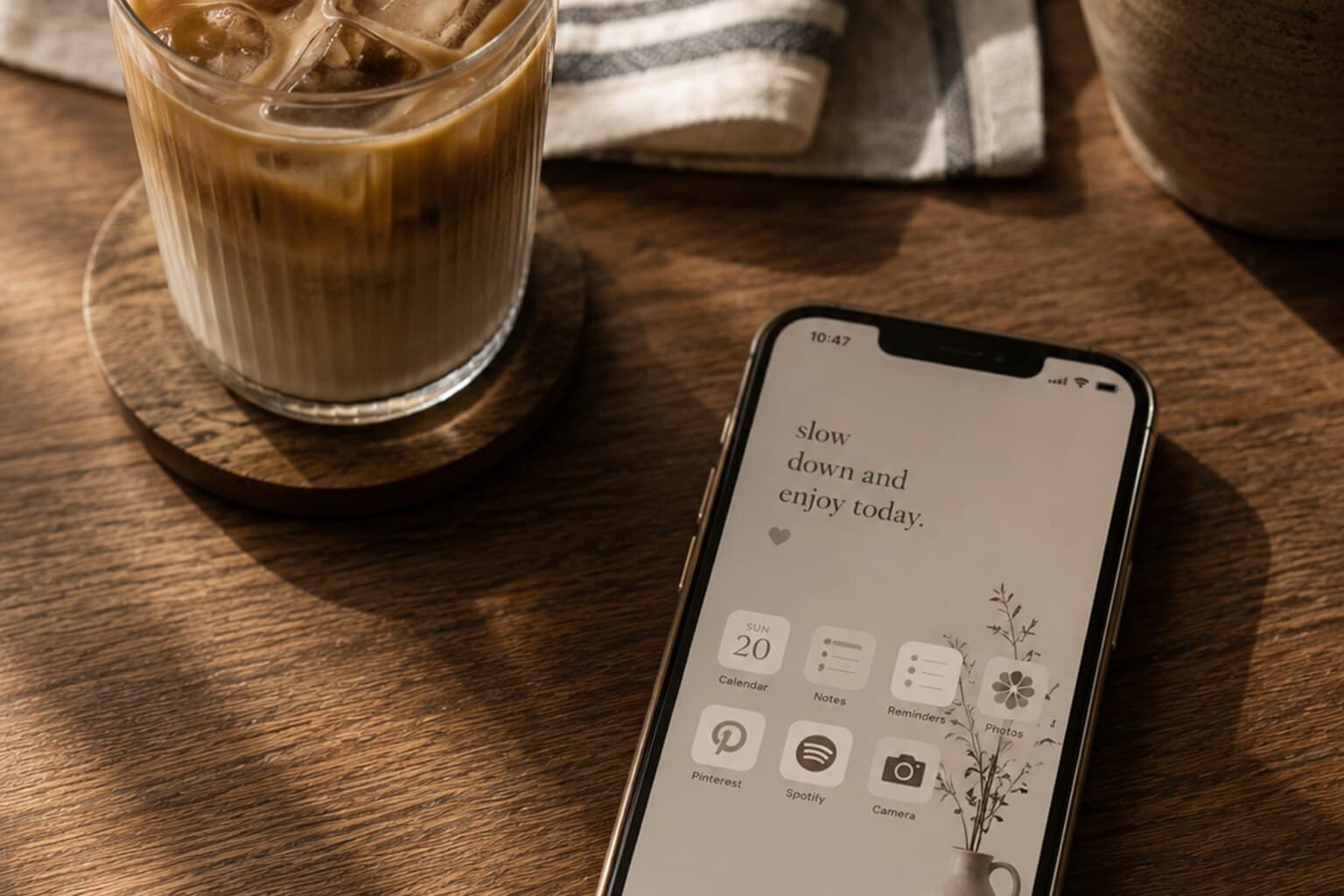 A phone with a simple, calm home screen resting face-up on a wooden table.