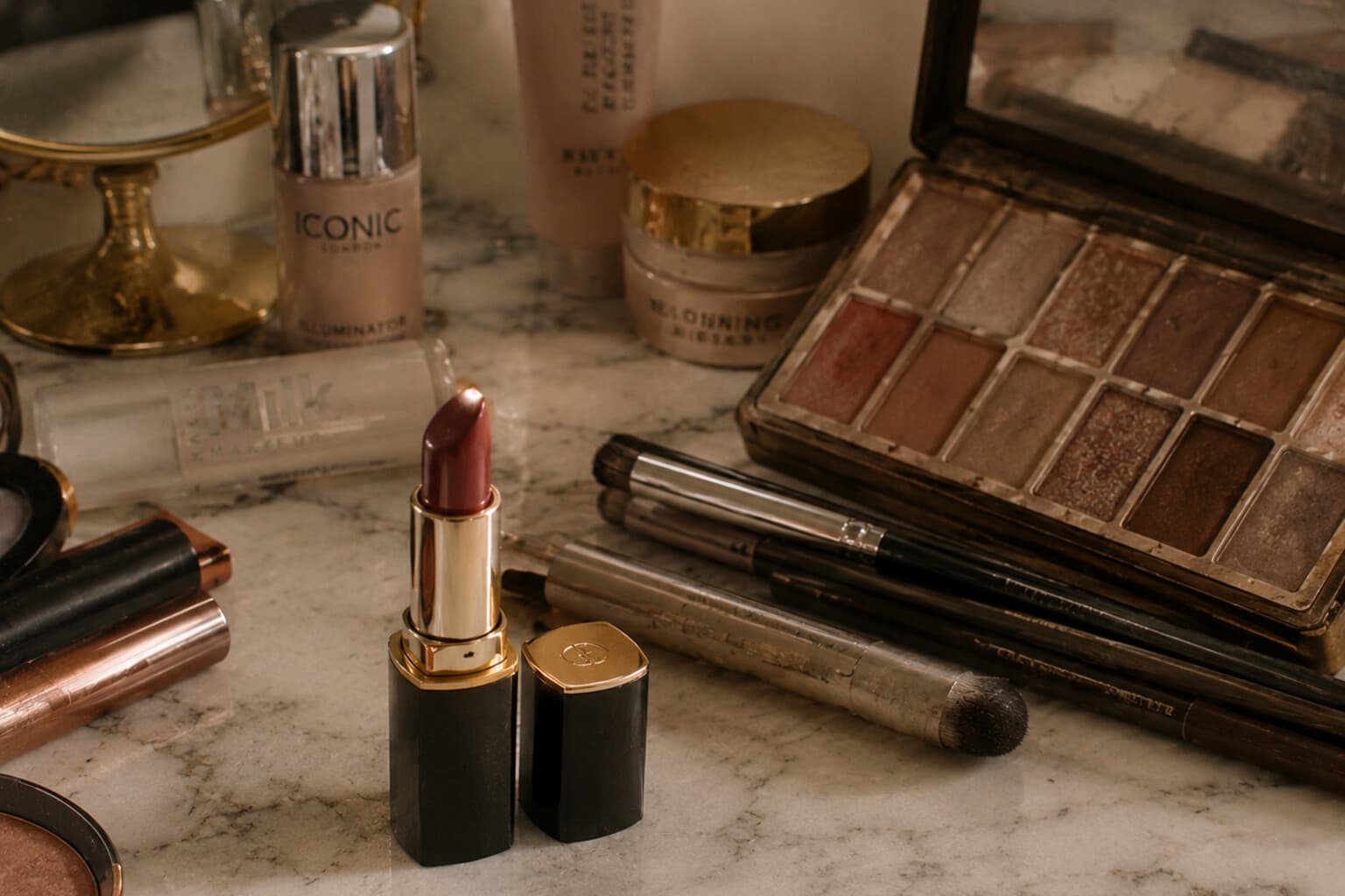 A single new lipstick considered beside an existing, well-used makeup collection.