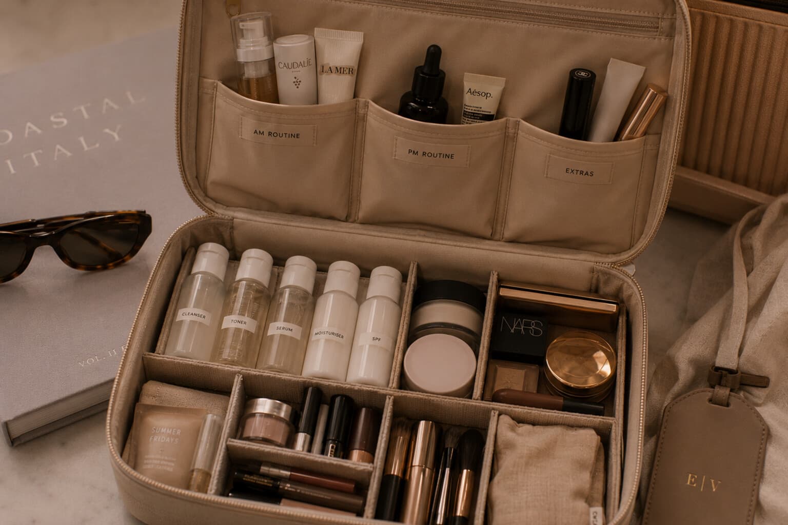 A structured travel beauty case with decanted skincare and makeup packed by routine.