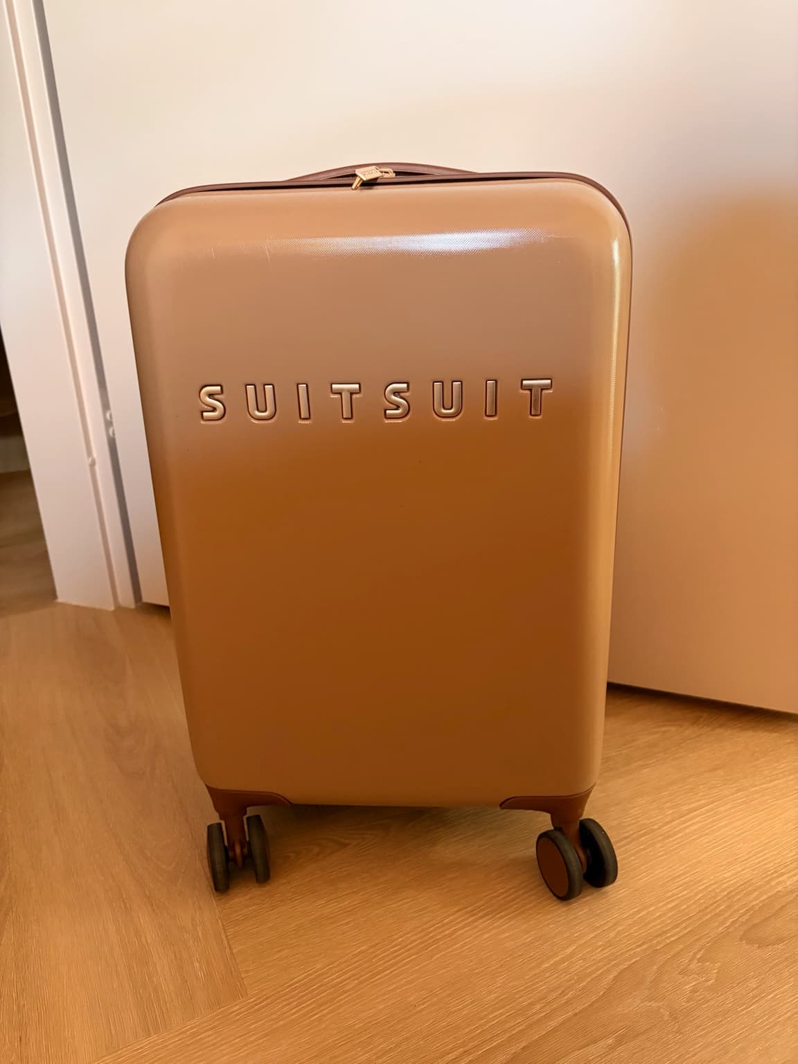 Brown SUITSUIT cabin suitcase with gold details in Esther's home.