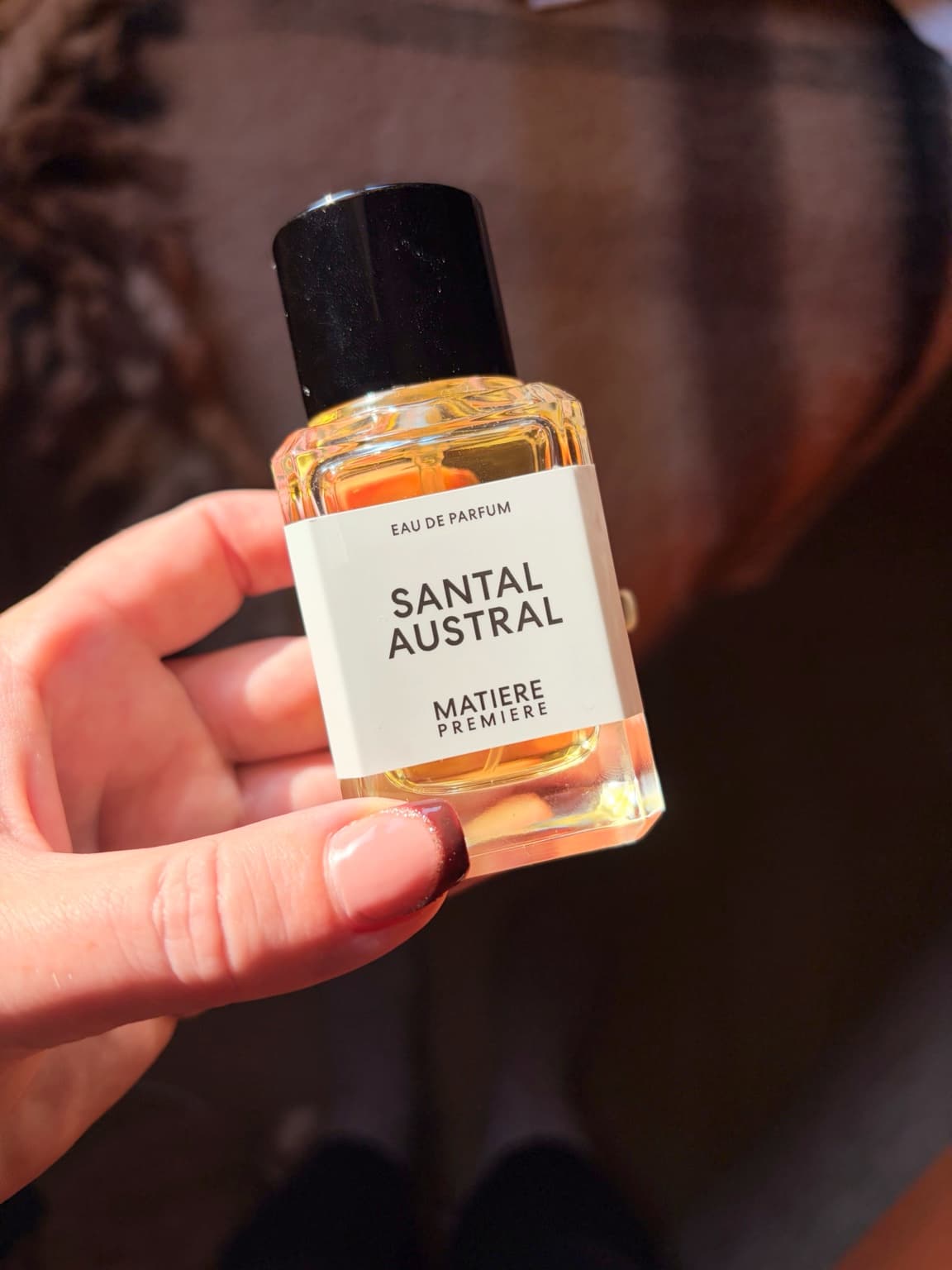 Bottle of Matière Première Santal Austral eau de parfum held in warm autumn light.