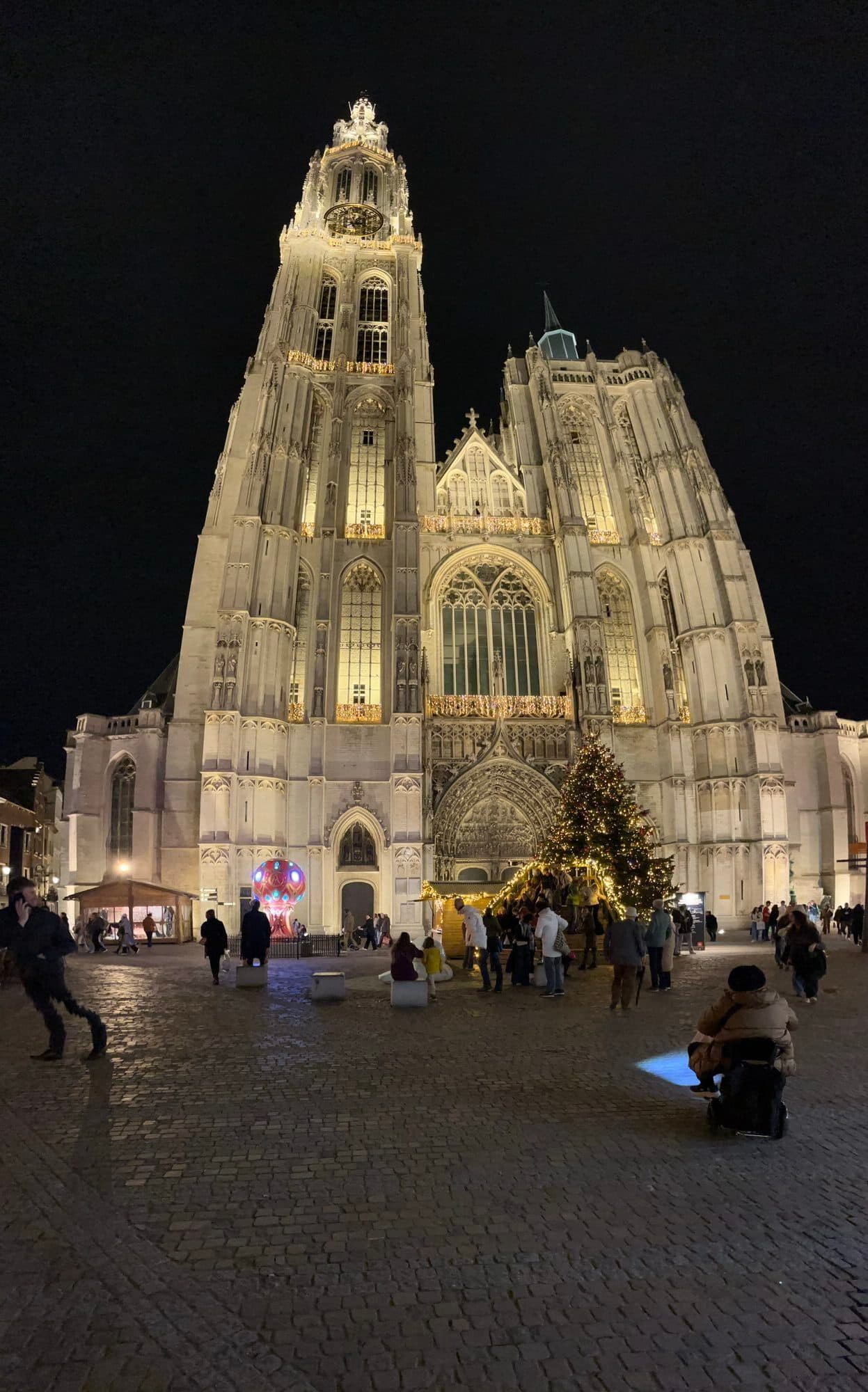 Onze-Lieve-Vrouwekathedraal lit up at night with a Christmas tree and market stalls in front