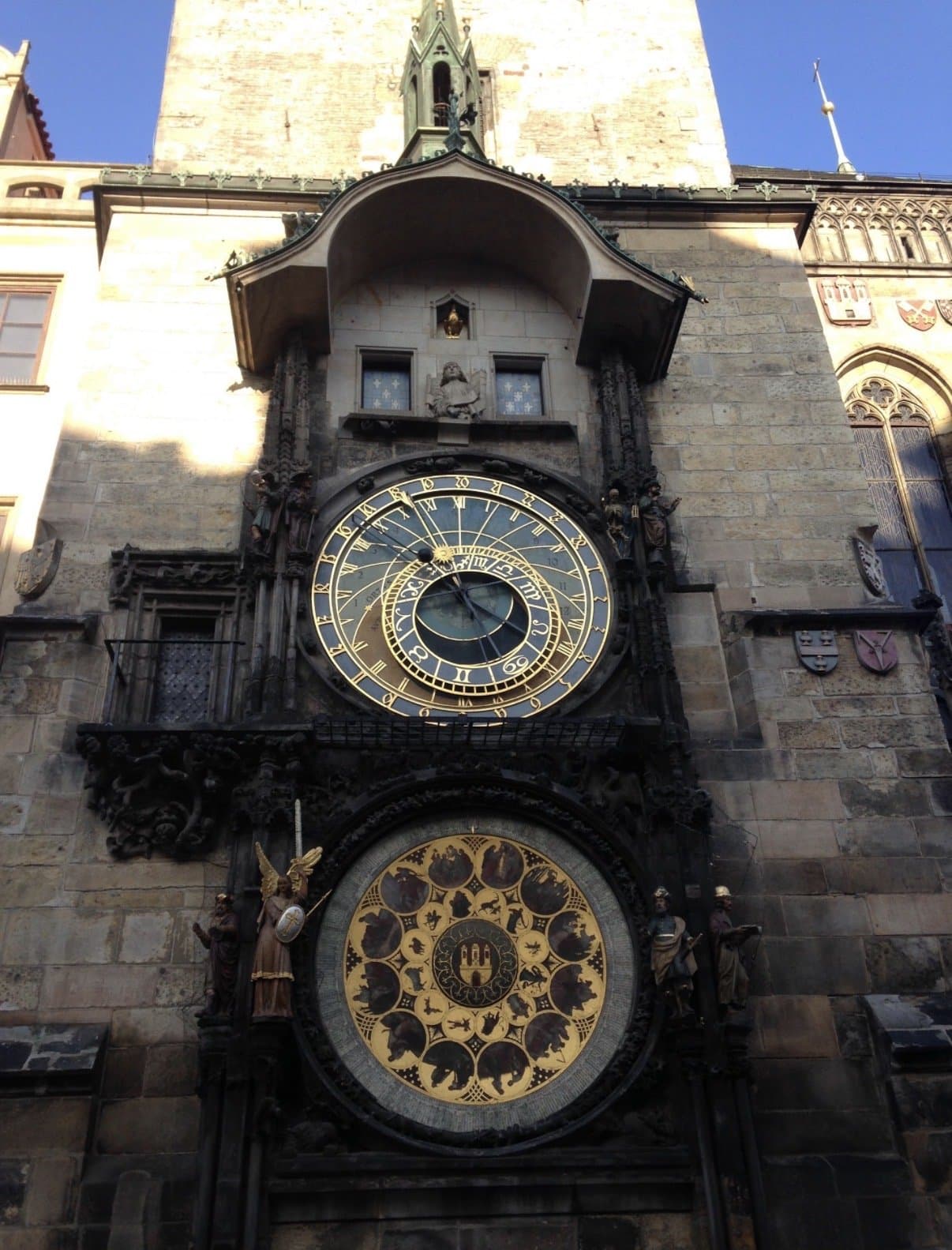 The ornate astronomical clock on the tower of Prague's Old Town Hall against a blue sky.