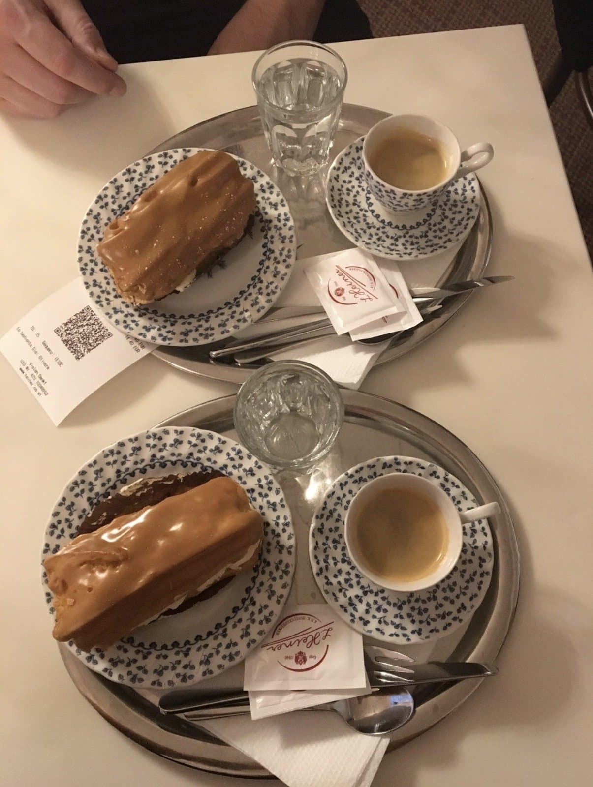 Two plates of layered cake and espresso cups on patterned porcelain at a Viennese café table.
