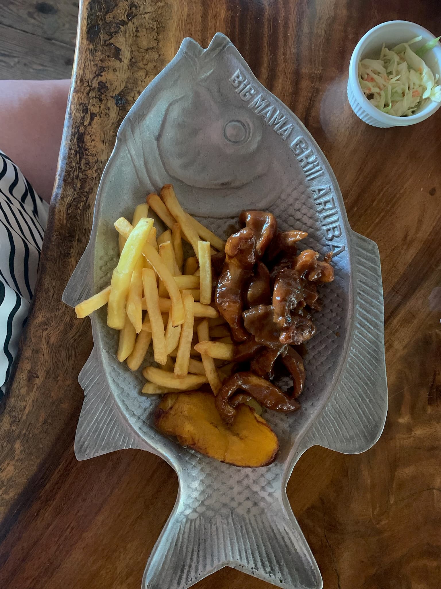 Casual Aruban meal served in a fish-shaped dish at Big Mama Grill, Baby Beach