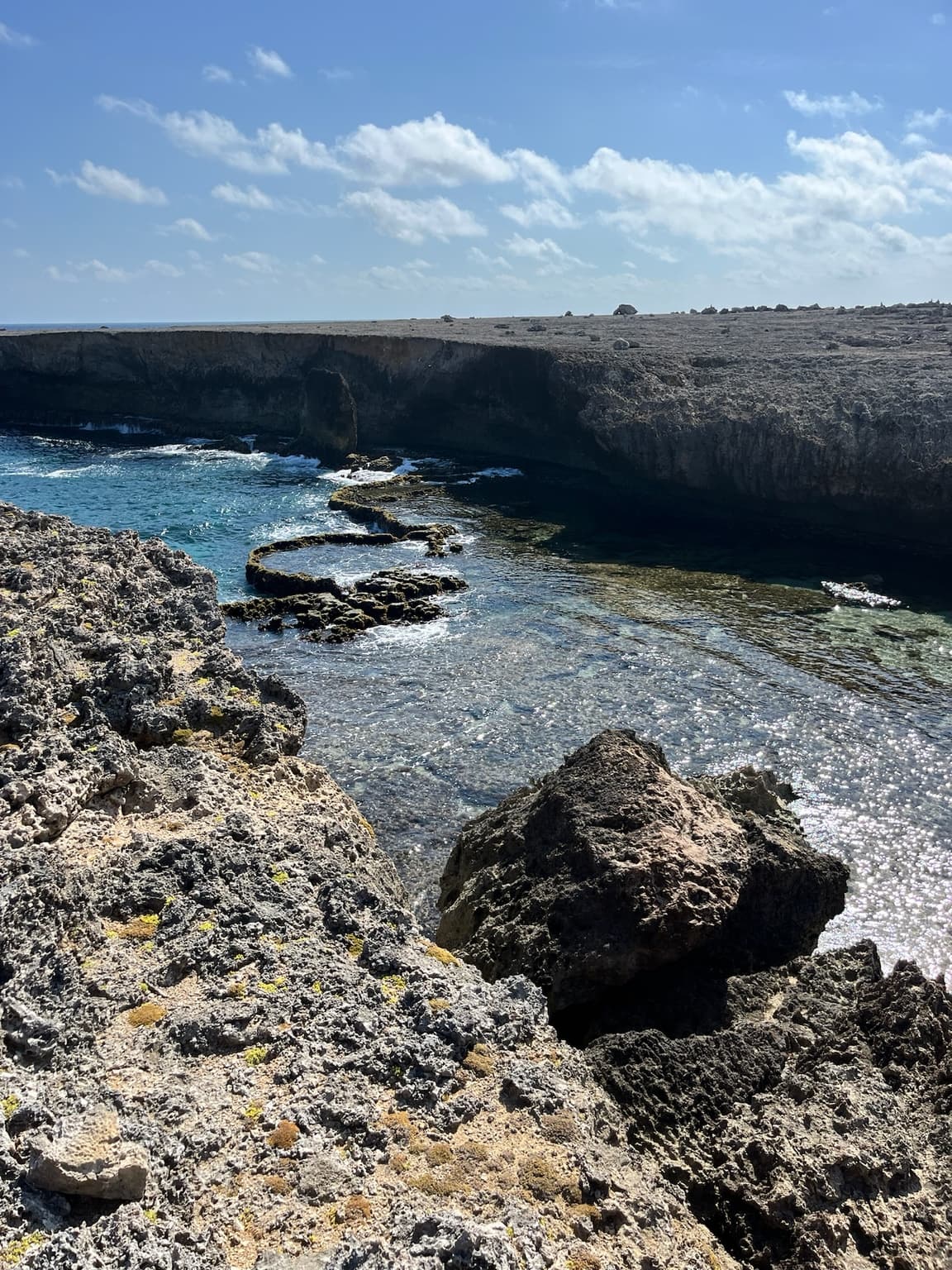Clear blue seawater surrounded by rugged dark limestone on Bonaire