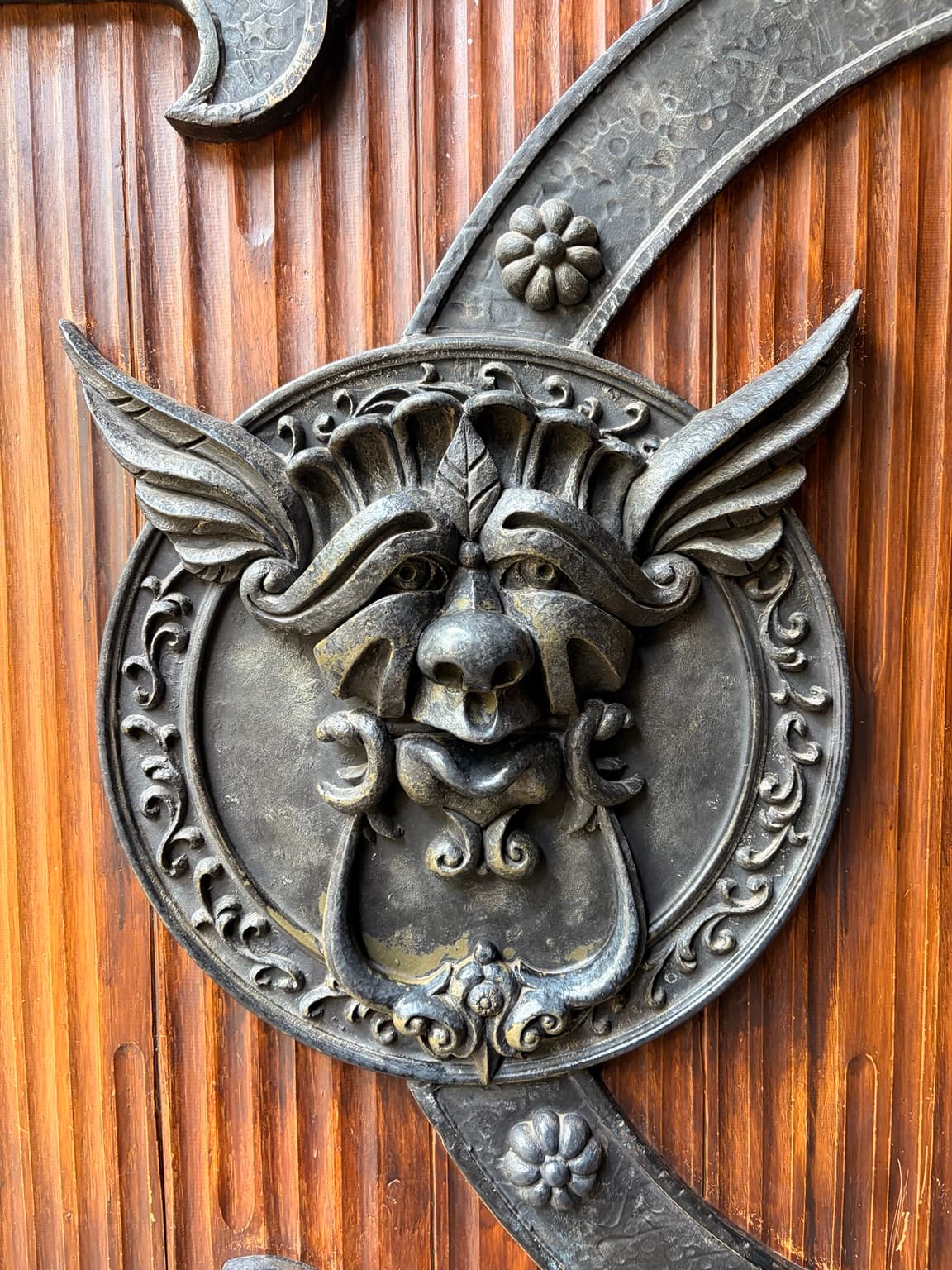 An ornate metal face and decorative ironwork on a wooden door at Efteling
