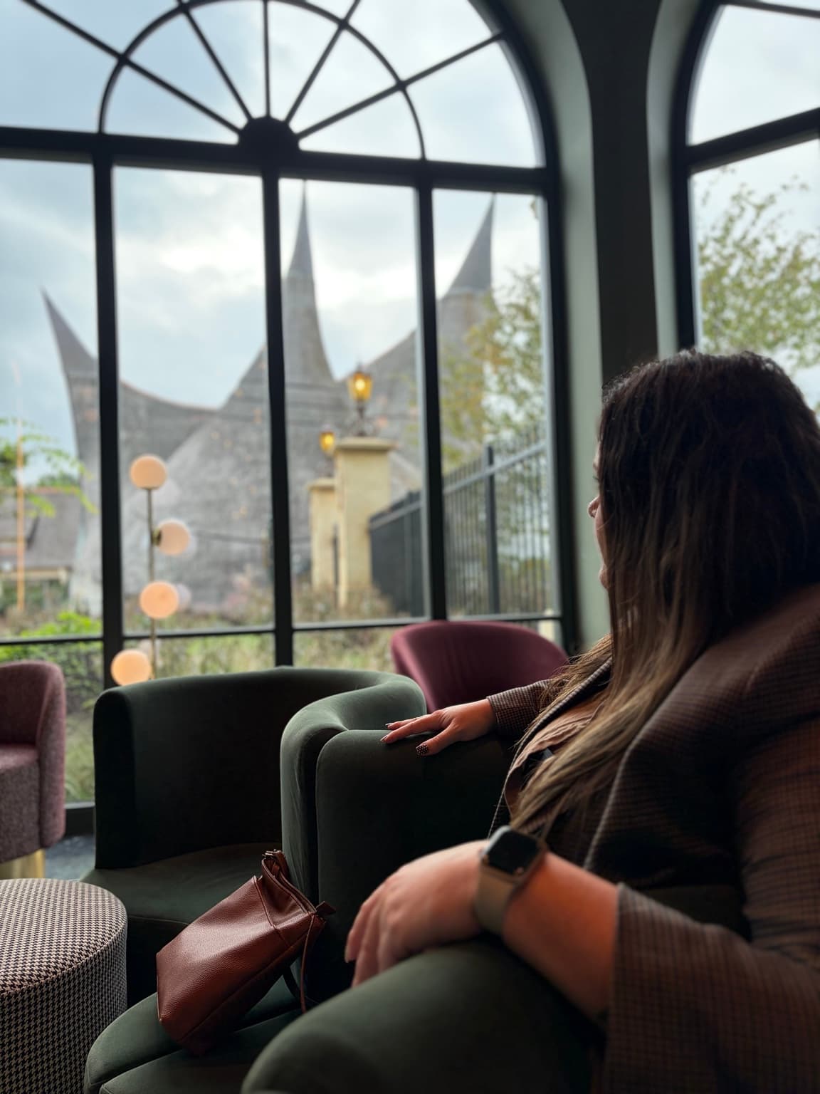 Esther sitting beside an arched window in the Efteling Grand Hotel, looking towards the park entrance