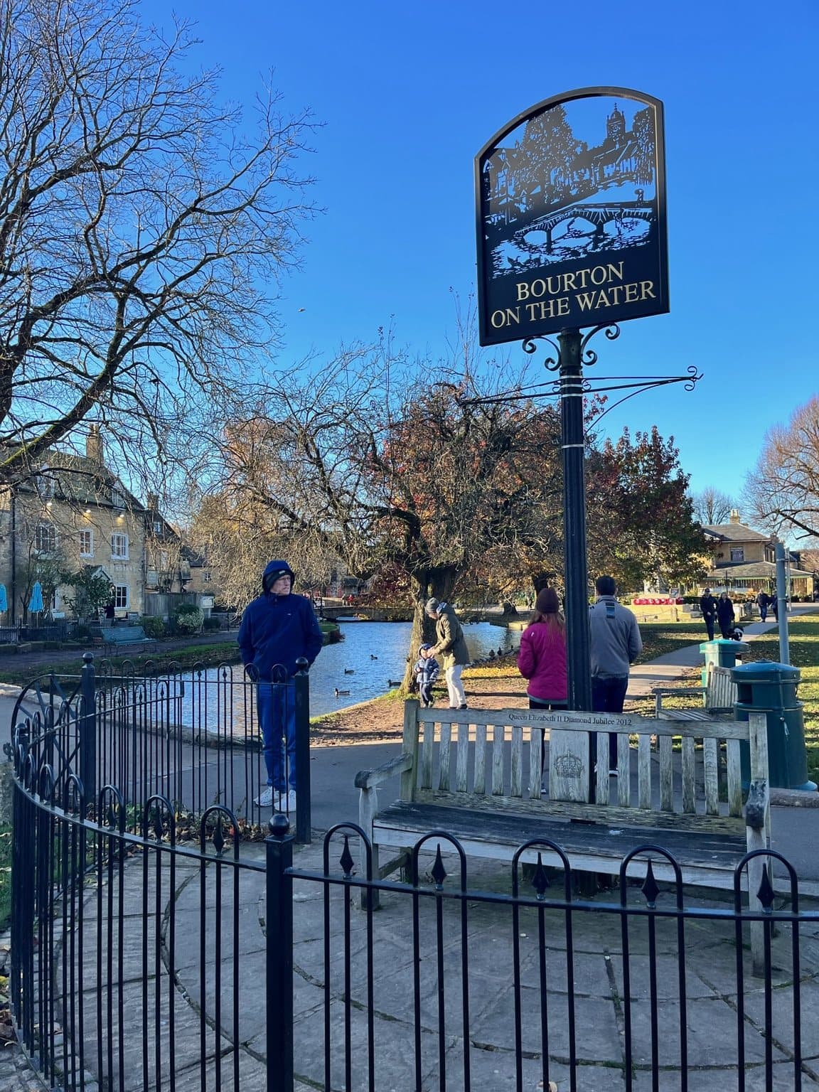 The Bourton-on-the-Water village sign beside the river