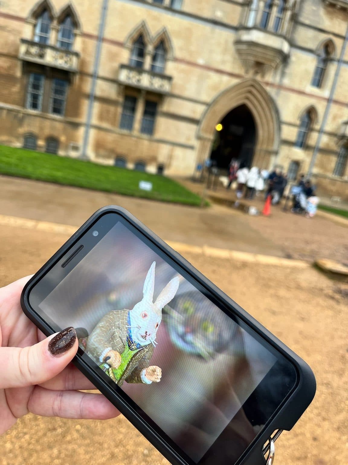 The White Rabbit from Alice in Wonderland on the Christ Church audio guide screen, held up outside Christ Church in Oxford