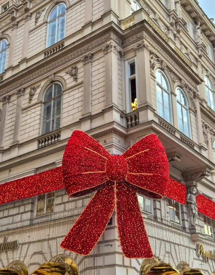 A giant illuminated red bow decorating a historic building in Vienna