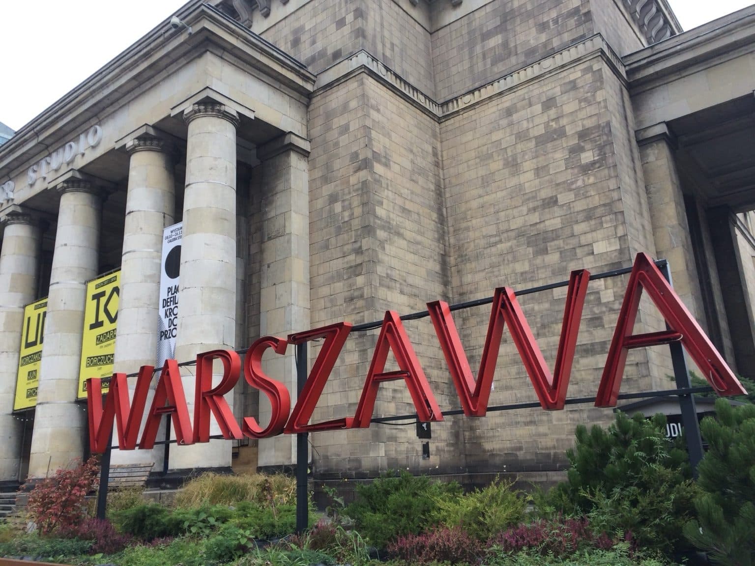 Large red “WARSZAWA” letters in front of the columns of a grand stone building